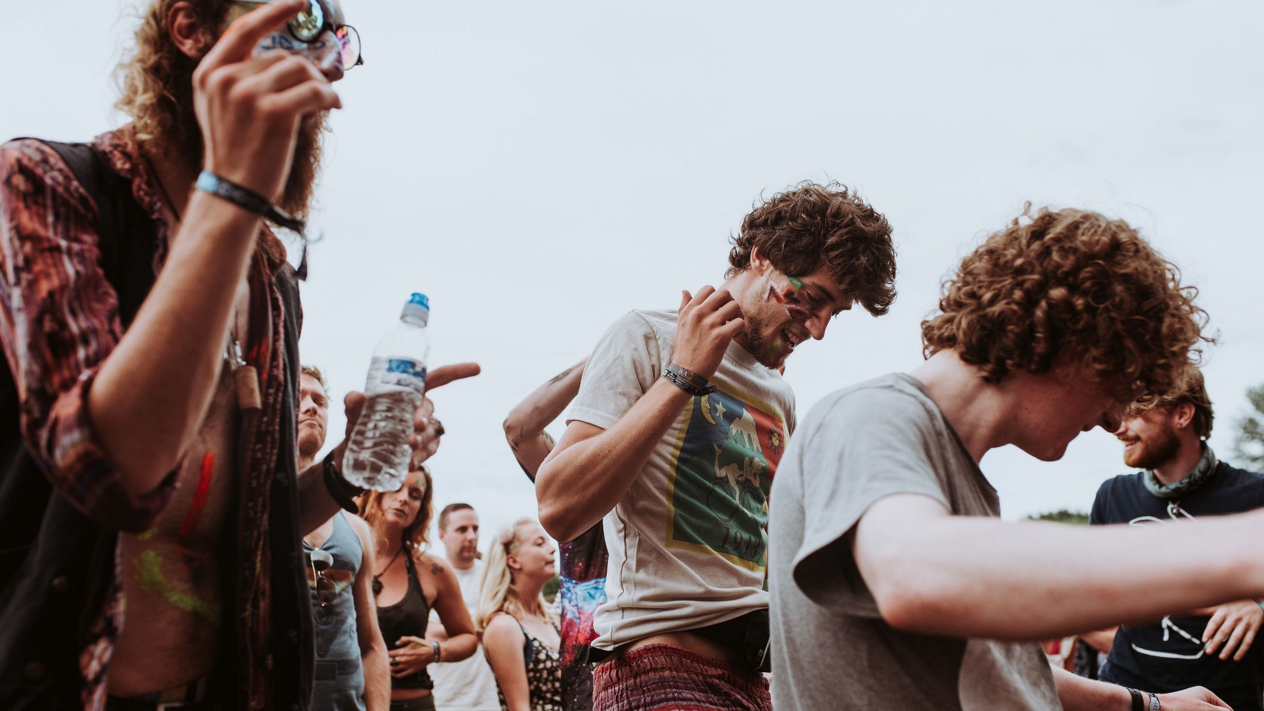 2560x1440 Wallpaper / a group of young people enjoying themselves at a music festival, cheerful festival crowd 4k wallpaper free download