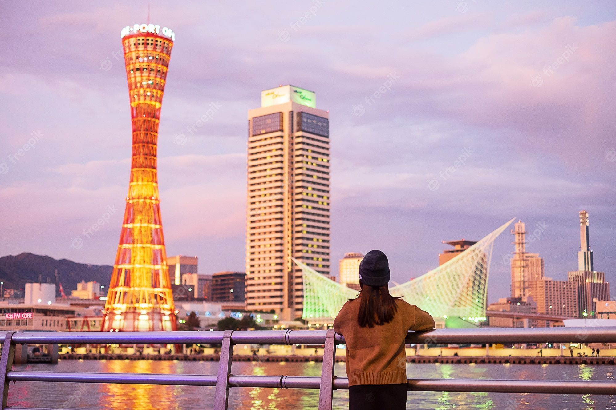 2000x1333 Premium Photo. Young woman traveling at kobe port near osaka, happy asian traveler looking beautiful modern buildings at sunset. landmark and popular for tourist attractions in kobe, hyogo, japan.asia travel concept