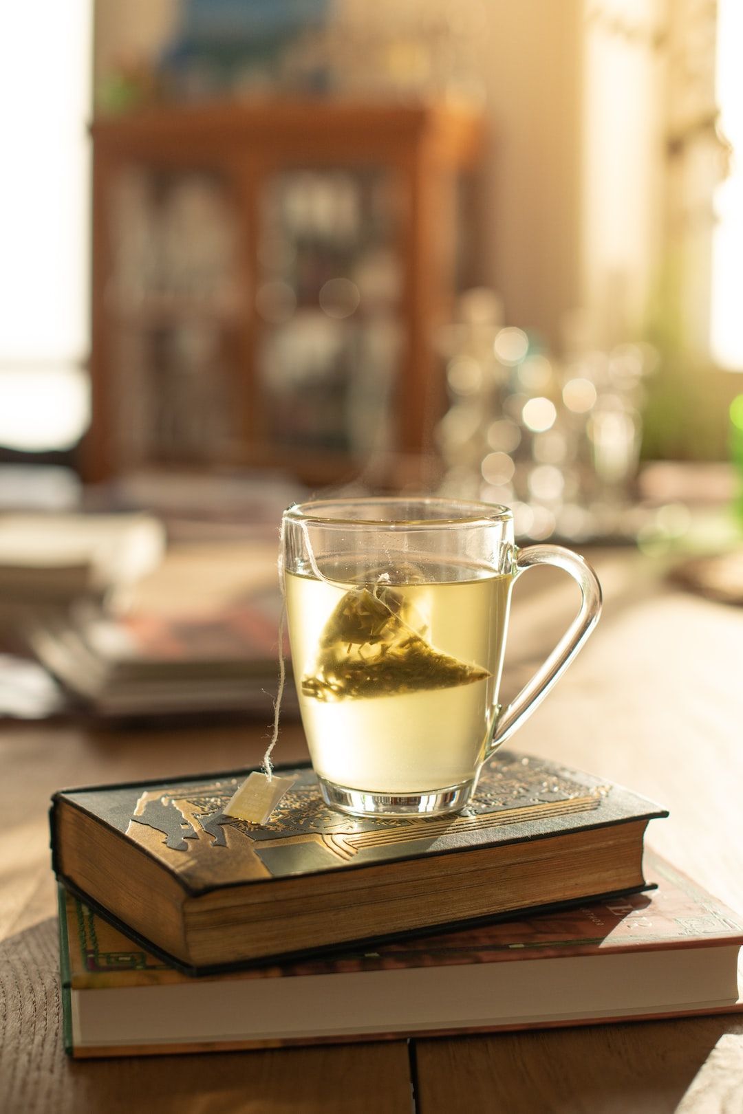 1080x1620 a steaming cup of herbal tea perched on a pile of vintage books Wallpaper Download