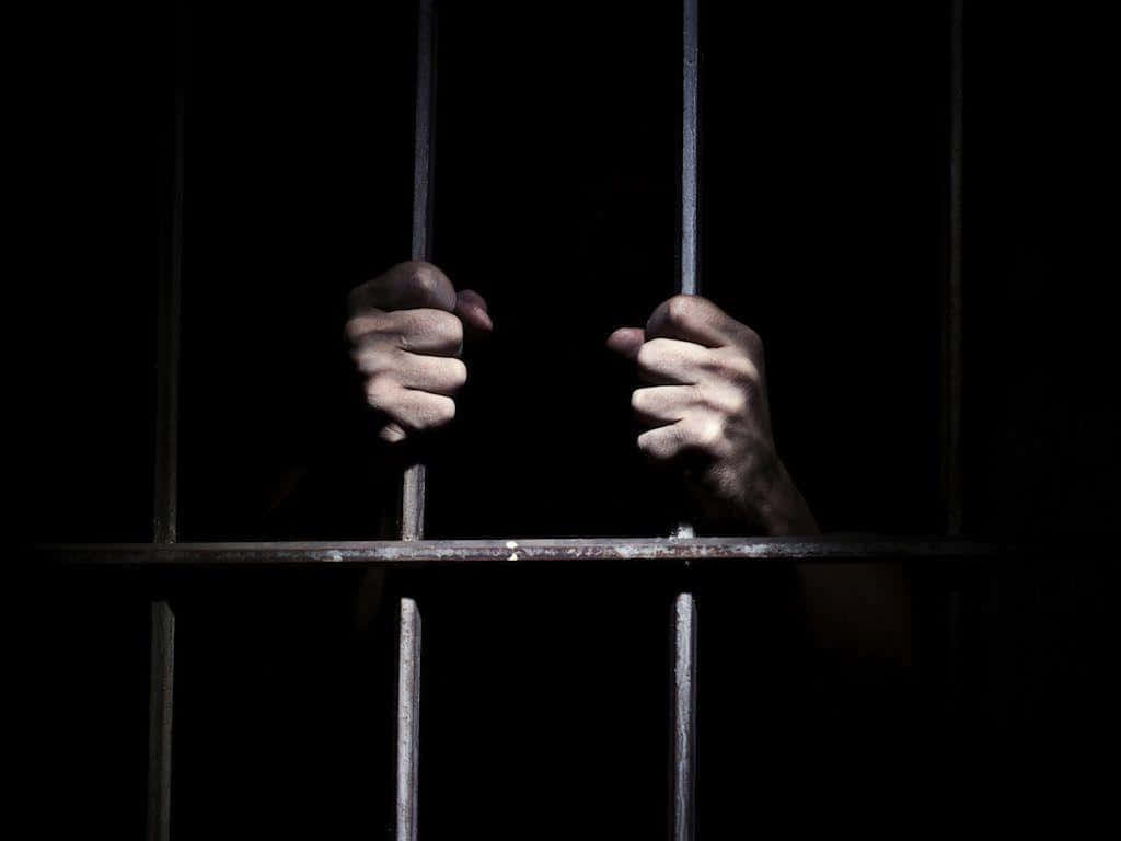 1024x768 Download A Person's Hands Are In A Jail Cell
