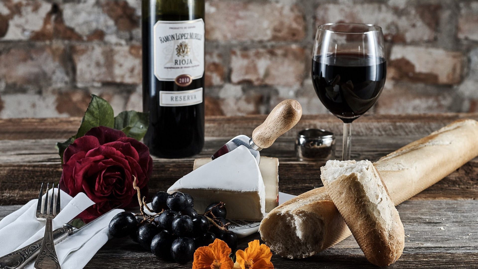 1920x1080 Wallpaper / still life, food, wine, bread, grapes, cheese, rose, flowers, knife, fork, napkin, wooden surface free download