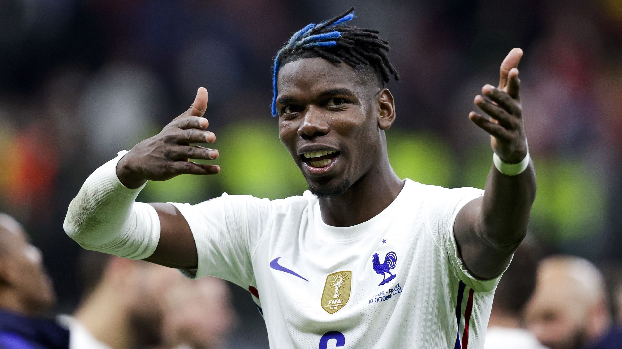 2560x1440 Paul Pogba Is Wearing White Sports Dress Standing In Blur Background HD France National Football Team Wallpaper