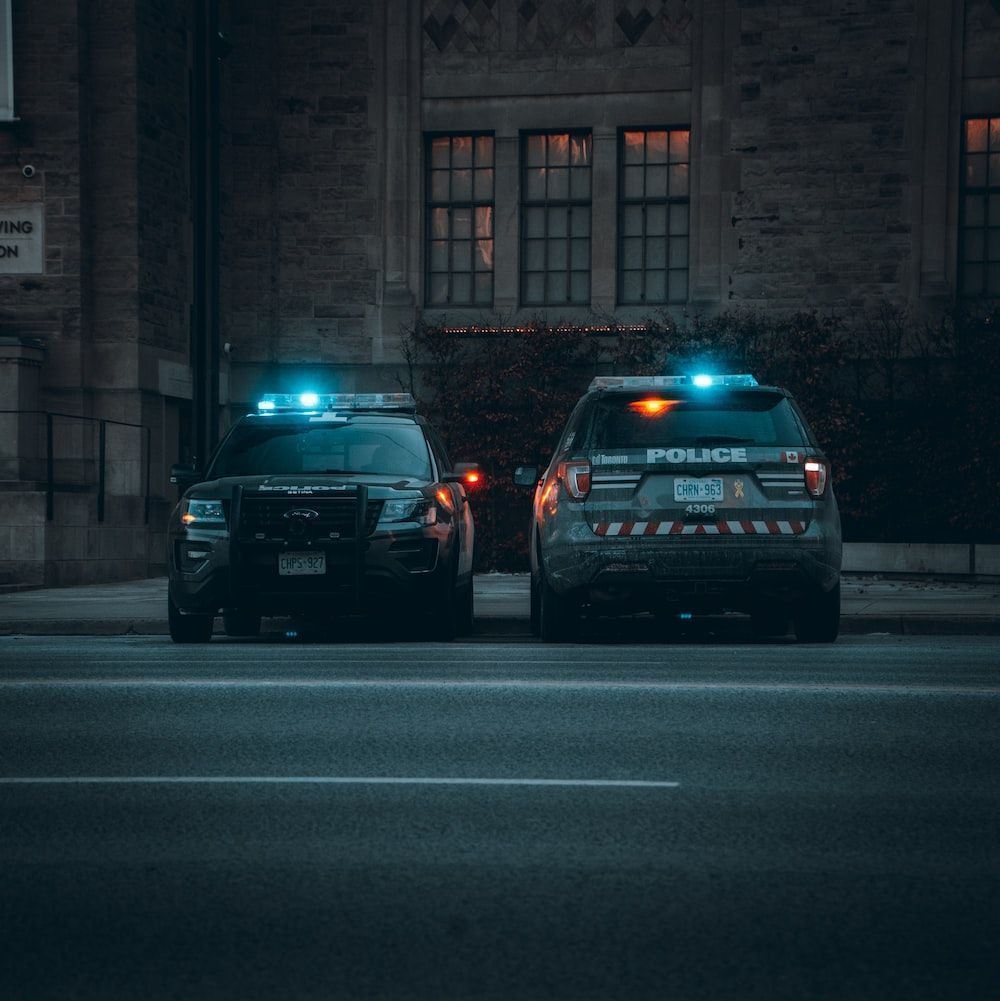 1000x1001 Two police cars parked on the side of the road photo