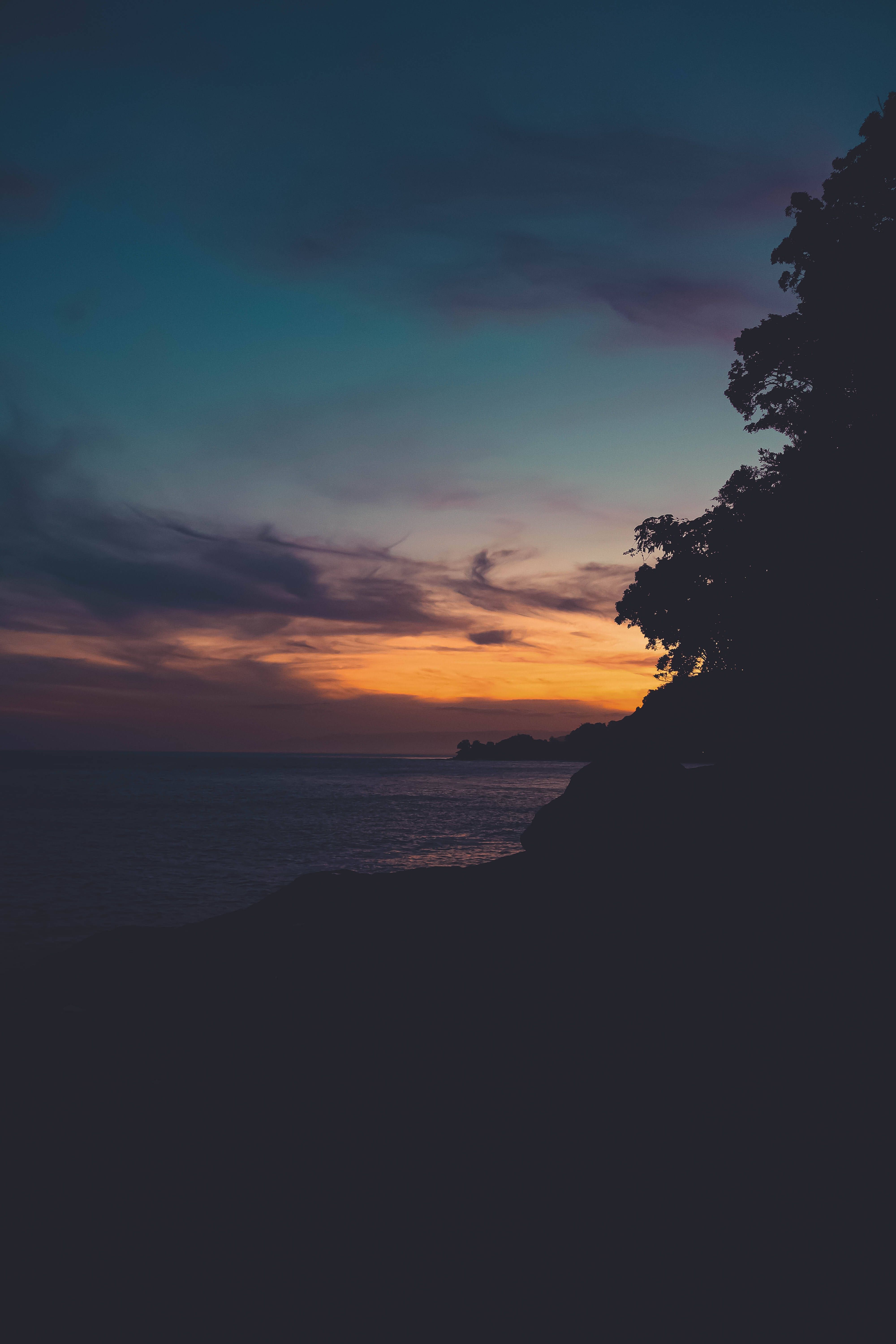 4000x6000 Download Bright shades of red and orange glow over a peaceful landscape during sunset Wallpaper