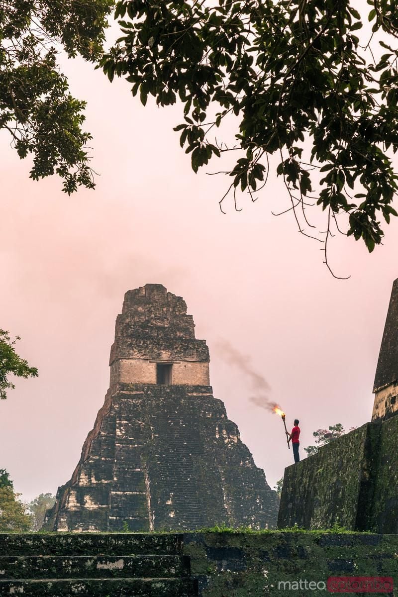 800x1200 Local man holding a torch in front of mayan temple, Tikal, Guatemala. Royalty Free Image