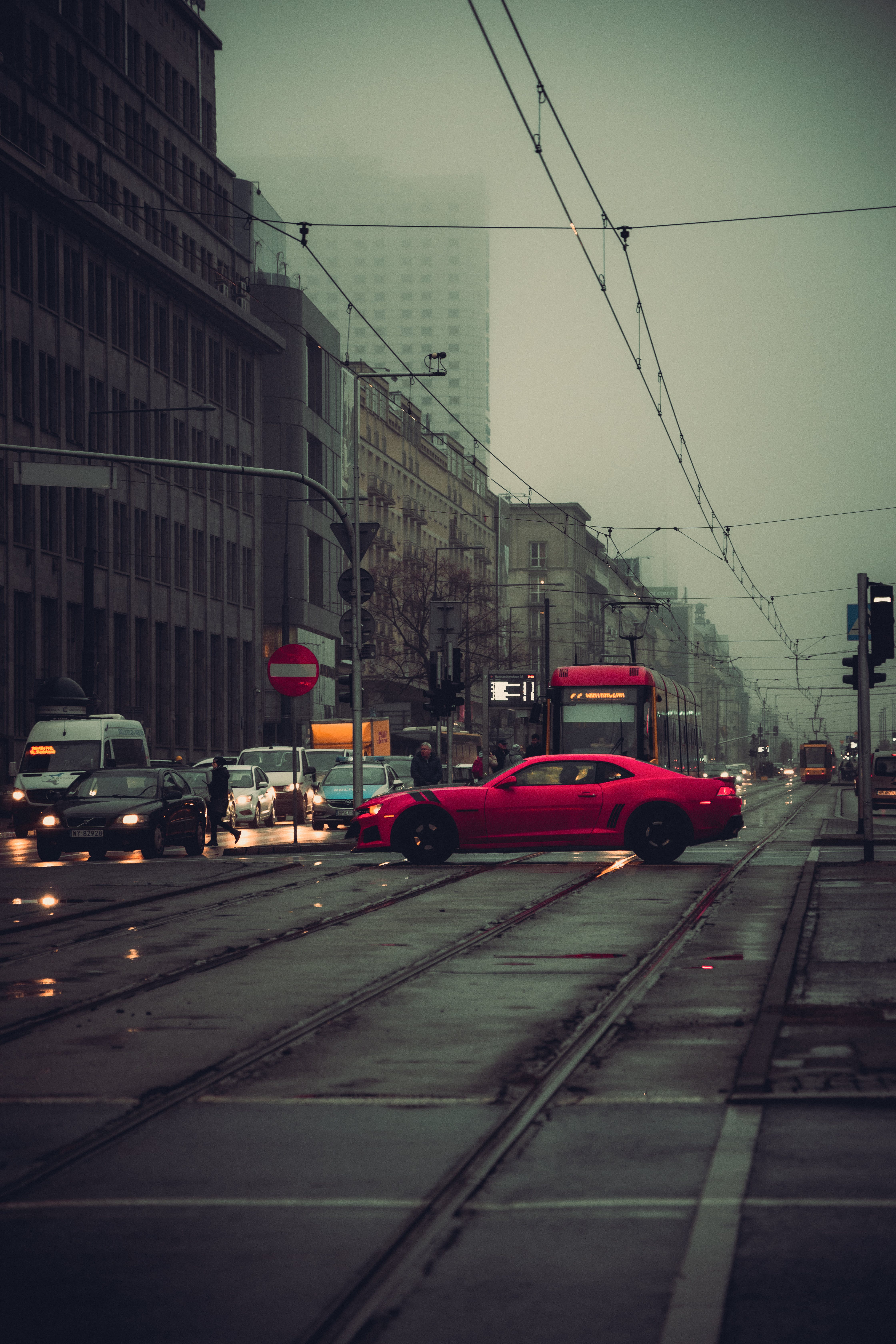 4480x6720 A red car driving down a street in the rain · Free