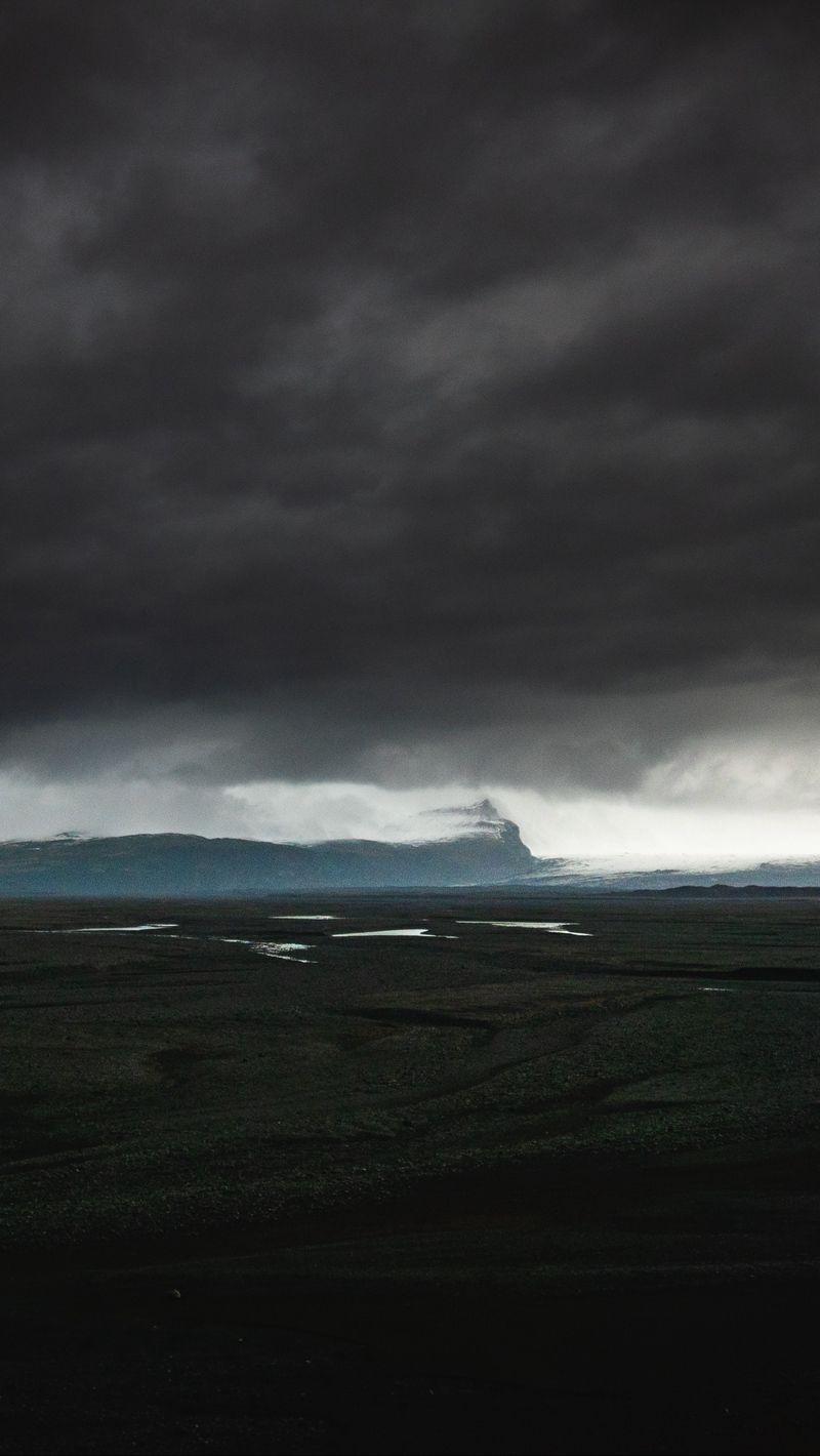 800x1420 Download wallpaper 800x1420 island, dark, clouds, iceland