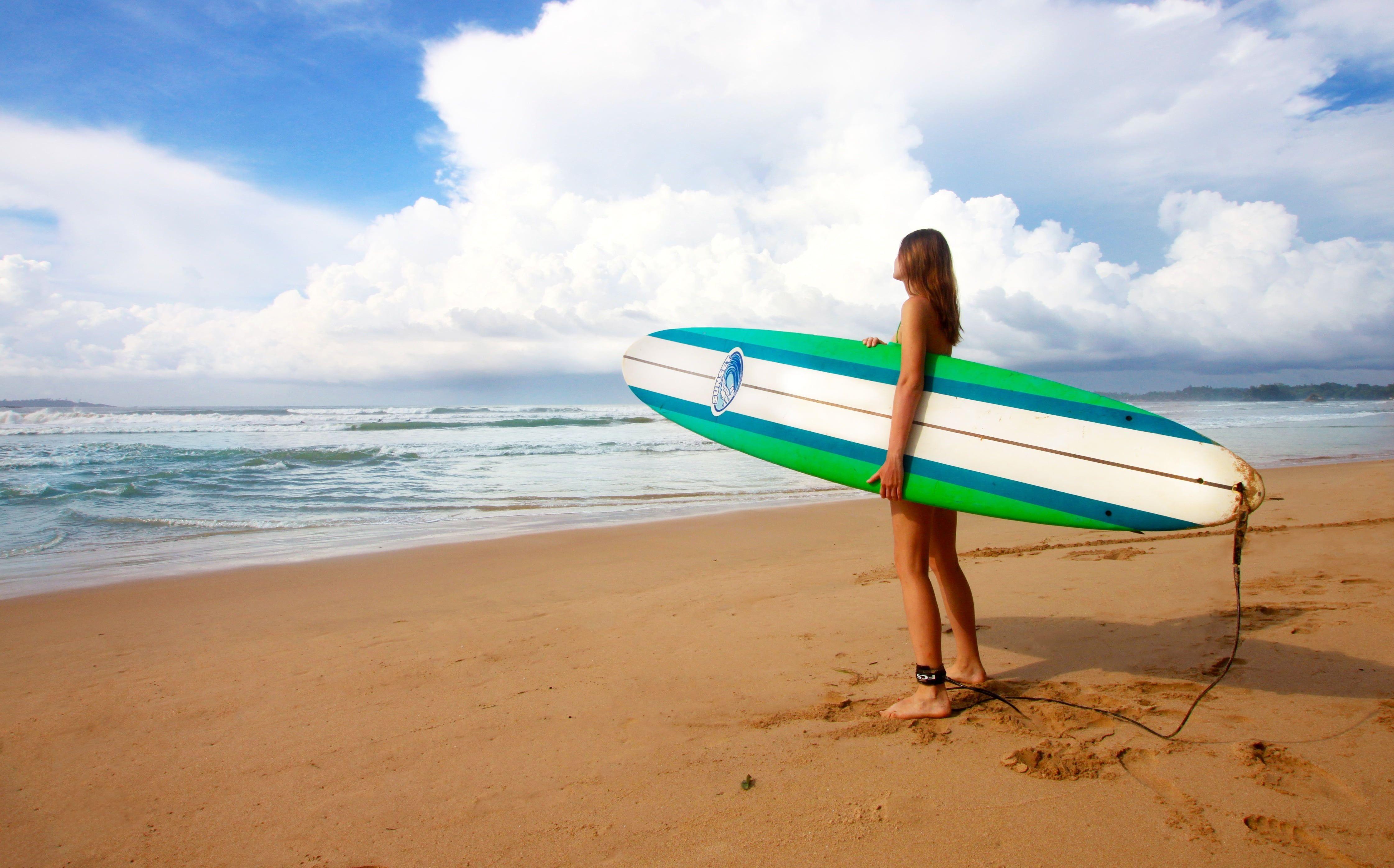 4485x2793 Woman golding green and white surfing board near sea under