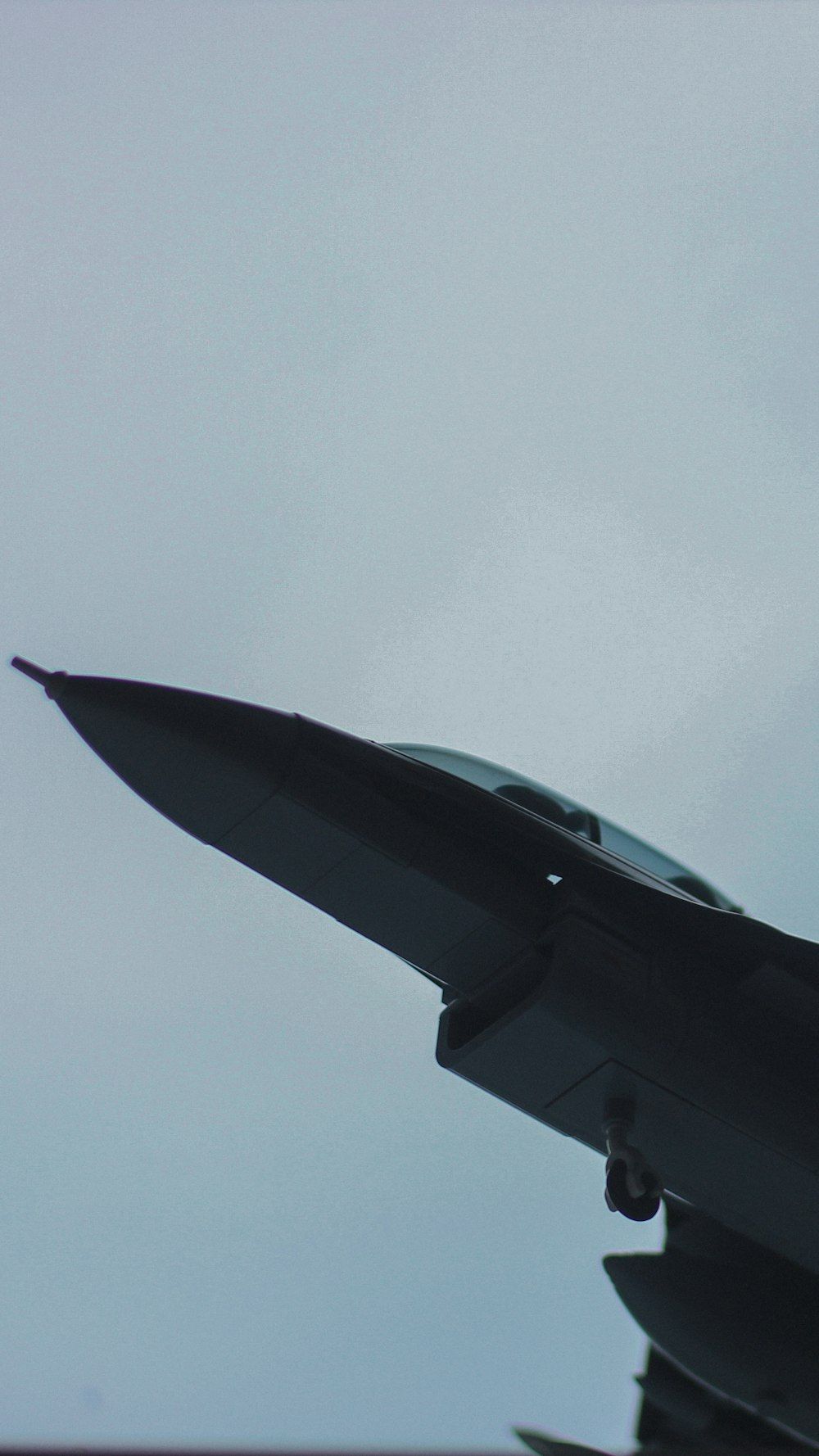1000x1778 fighter jet flying through a cloudy sky