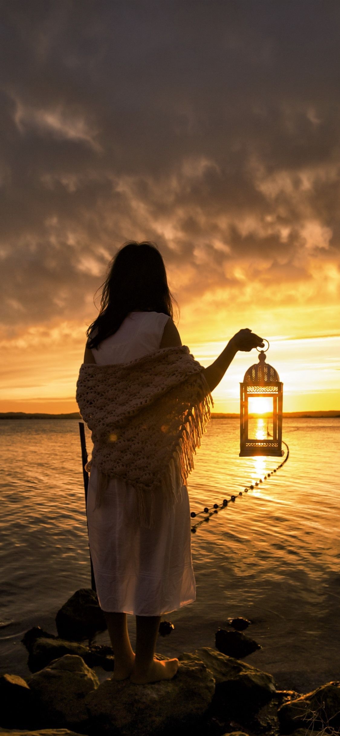 1125x2436 Girl, back view, lantern, sea, sunset