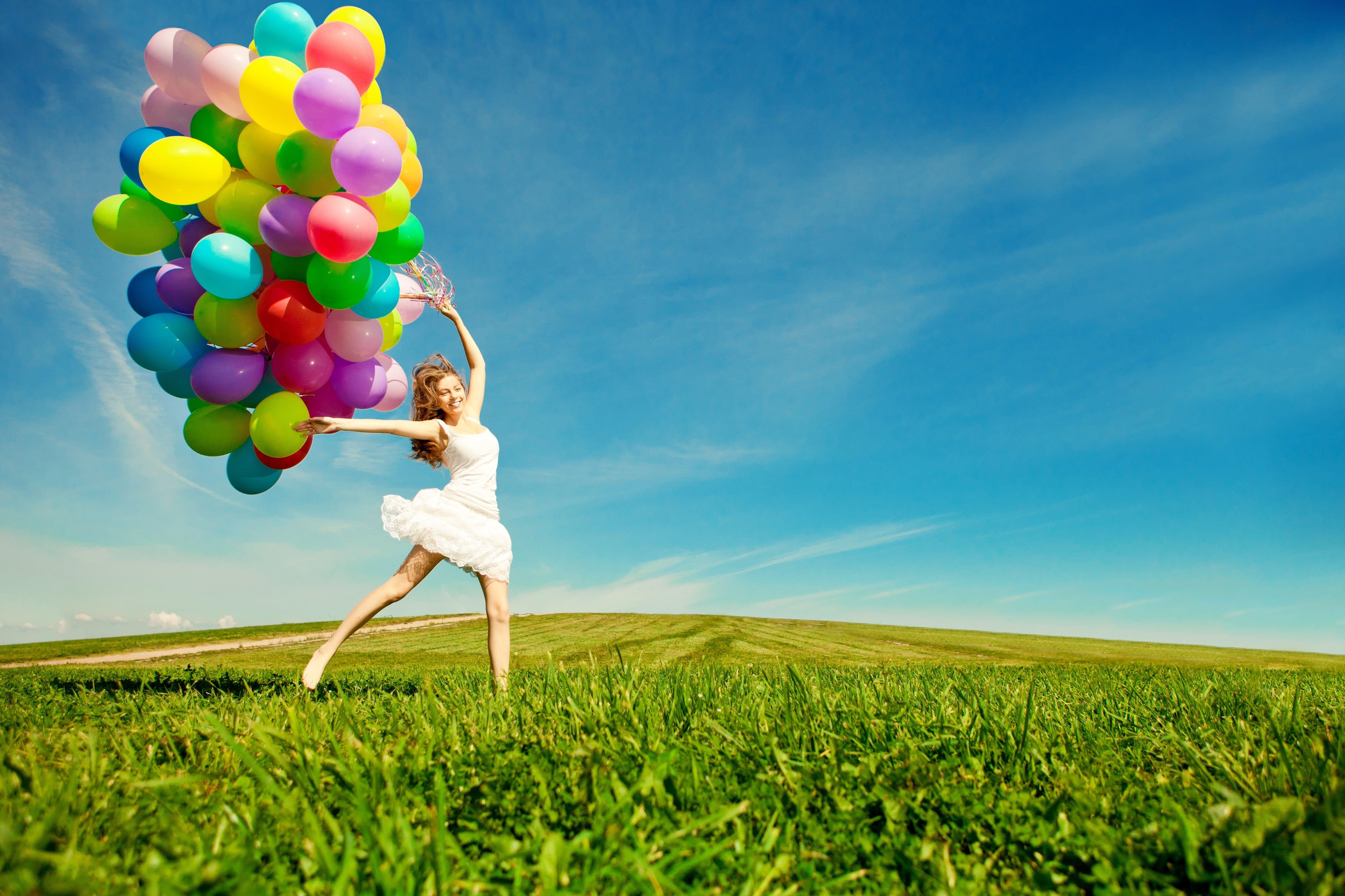 5000x3333 Woman Jumps On Green Grass Holds Assorted Color Balloons