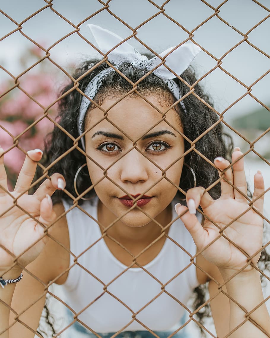 910x1138 woman holding chain link fence, female
