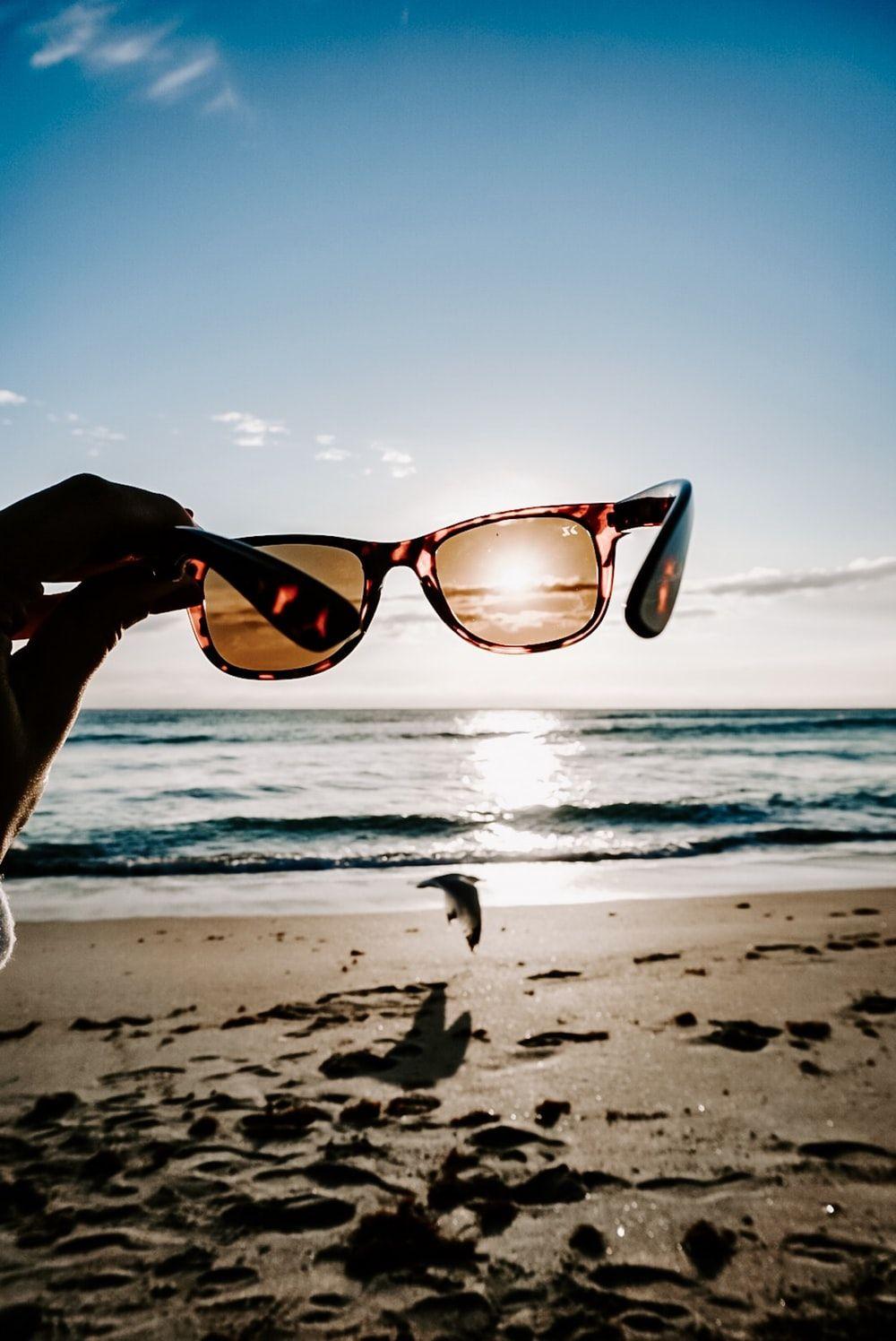 1000x1496 person holding sunglasses on beach during daytime photo