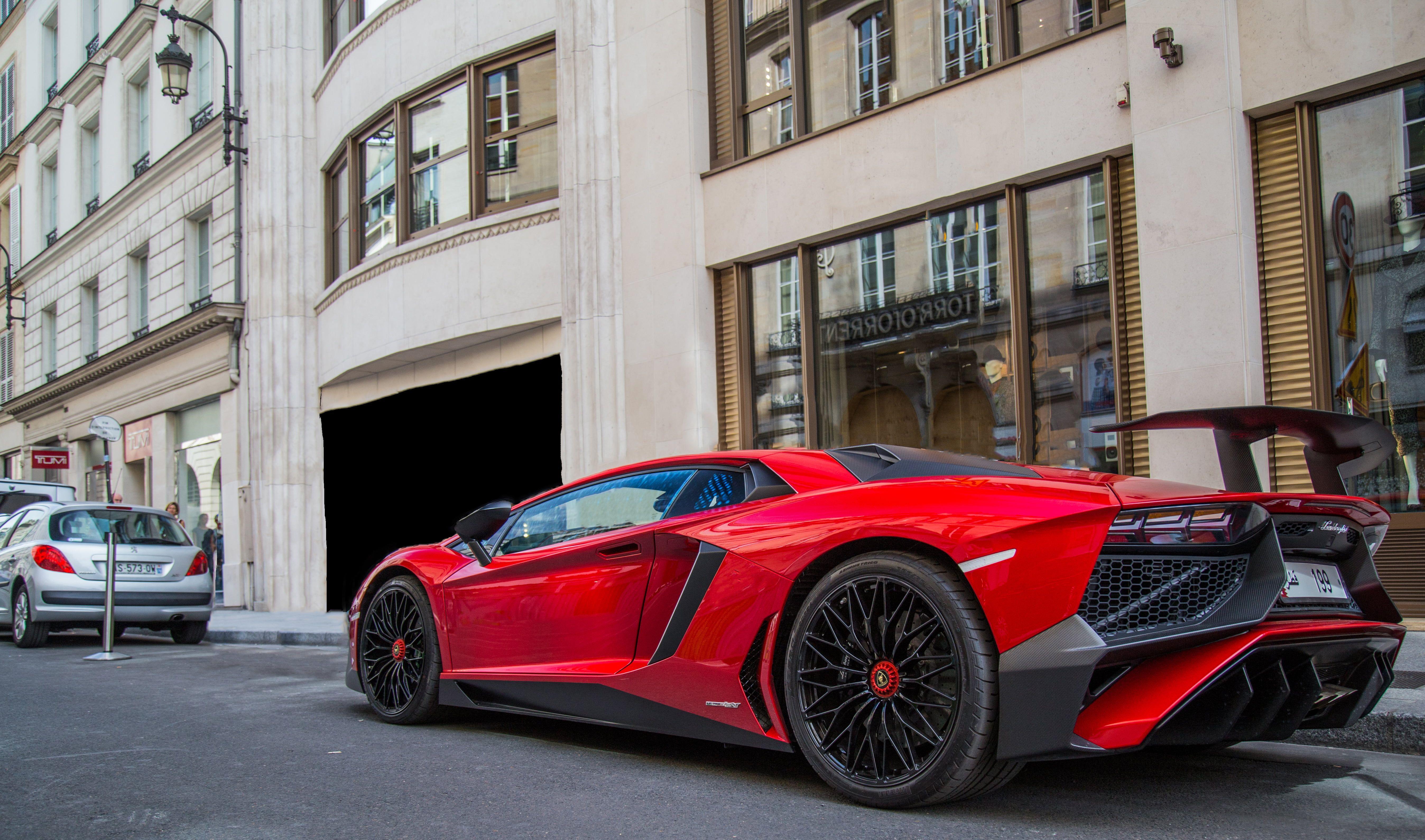 5392x3180 Red and black sports car infront of botiques HD wallpaper