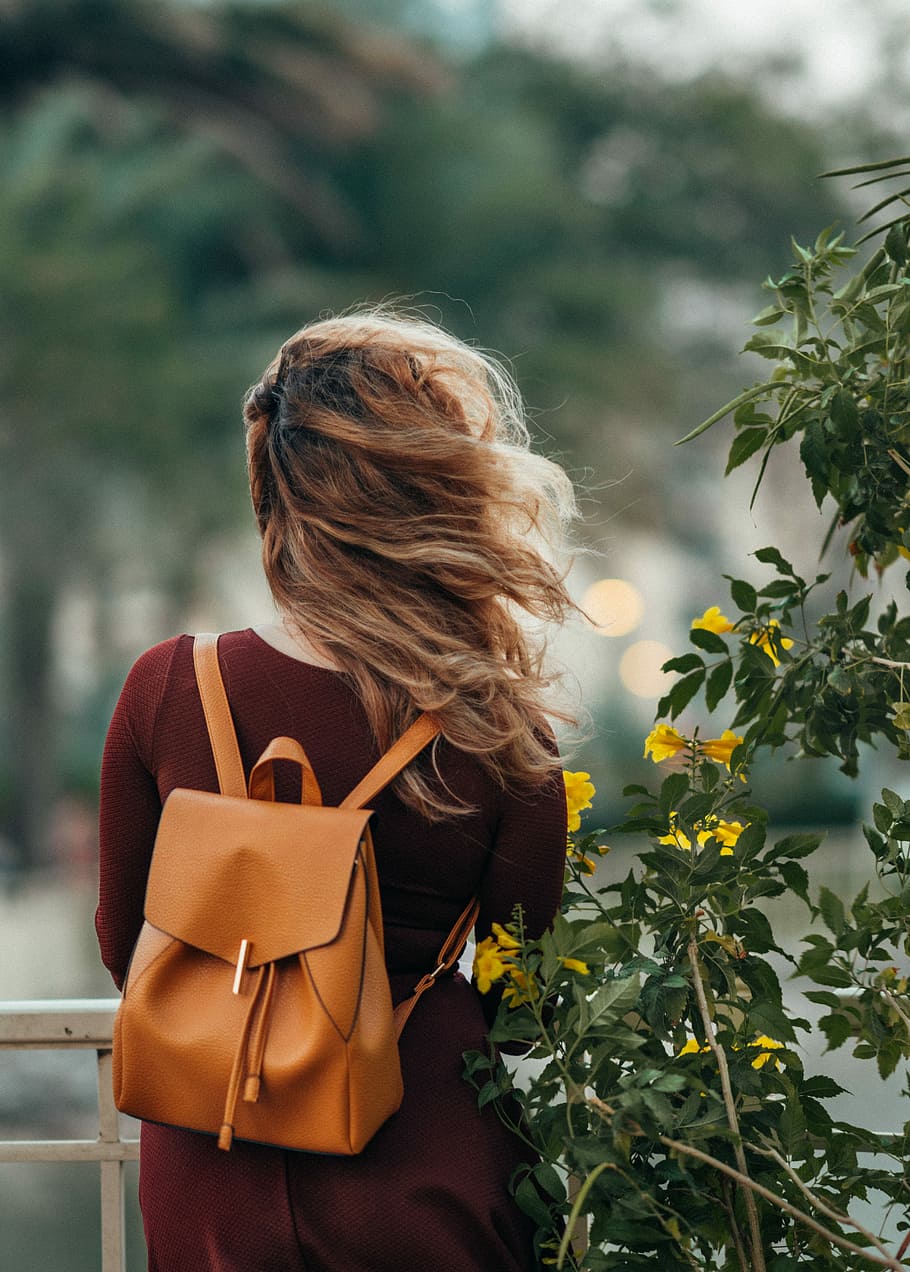 910x1272 woman carrying brown leather backpack