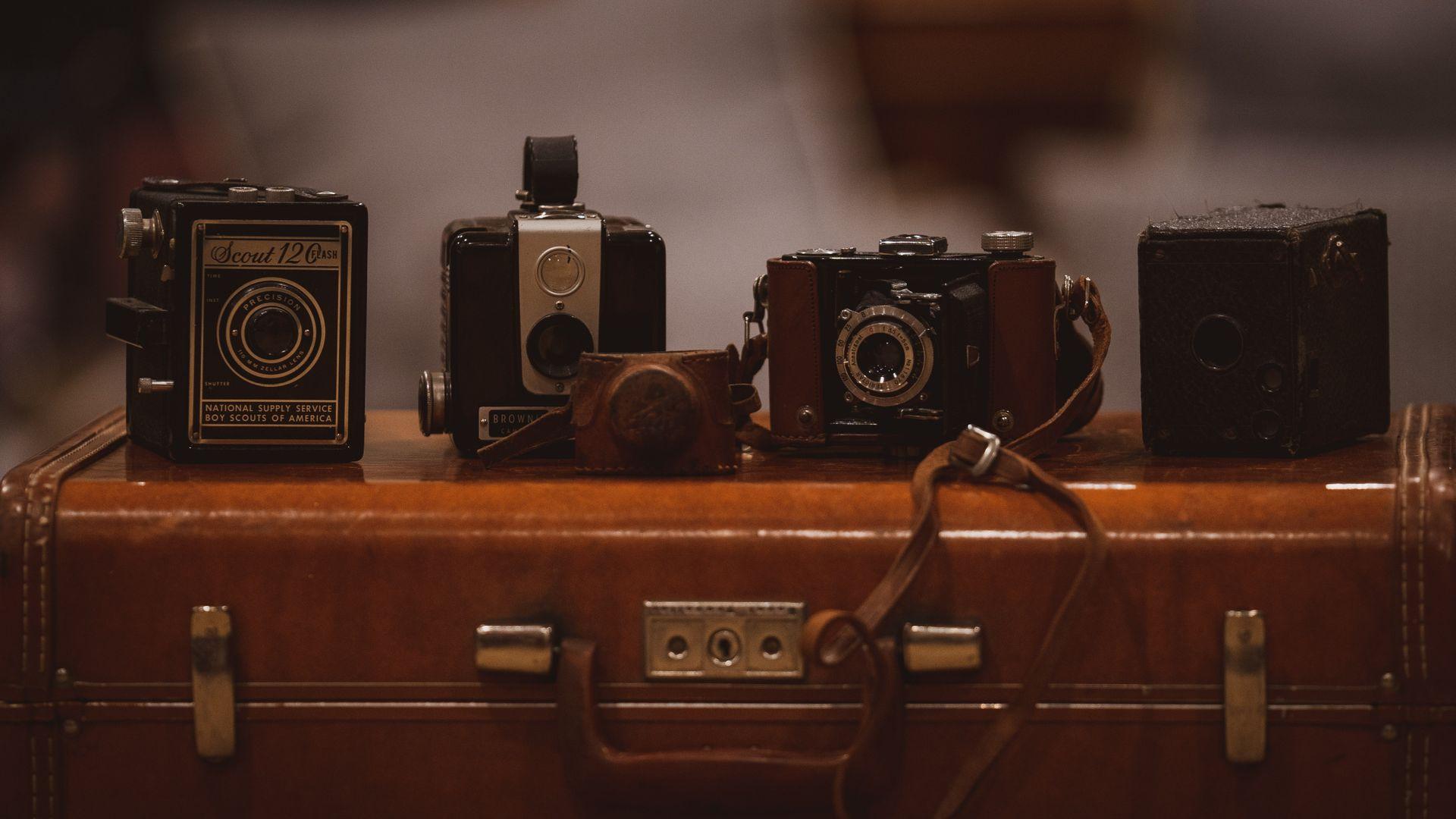 1920x1080 Four Assorted Color Cameras on Brown Suitcase Wallpaper