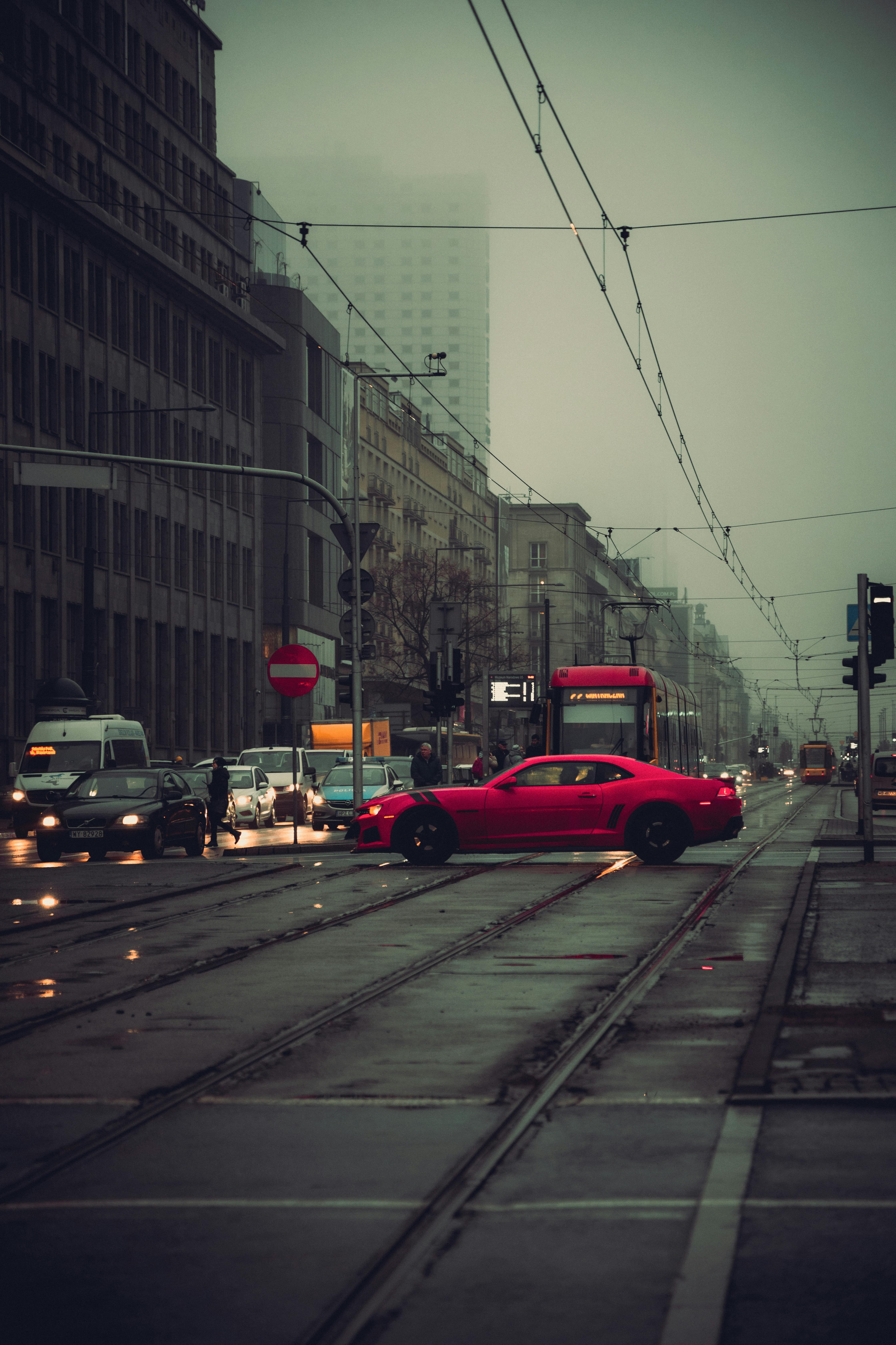 4480x6720 A red car driving down a street in the rain · Free