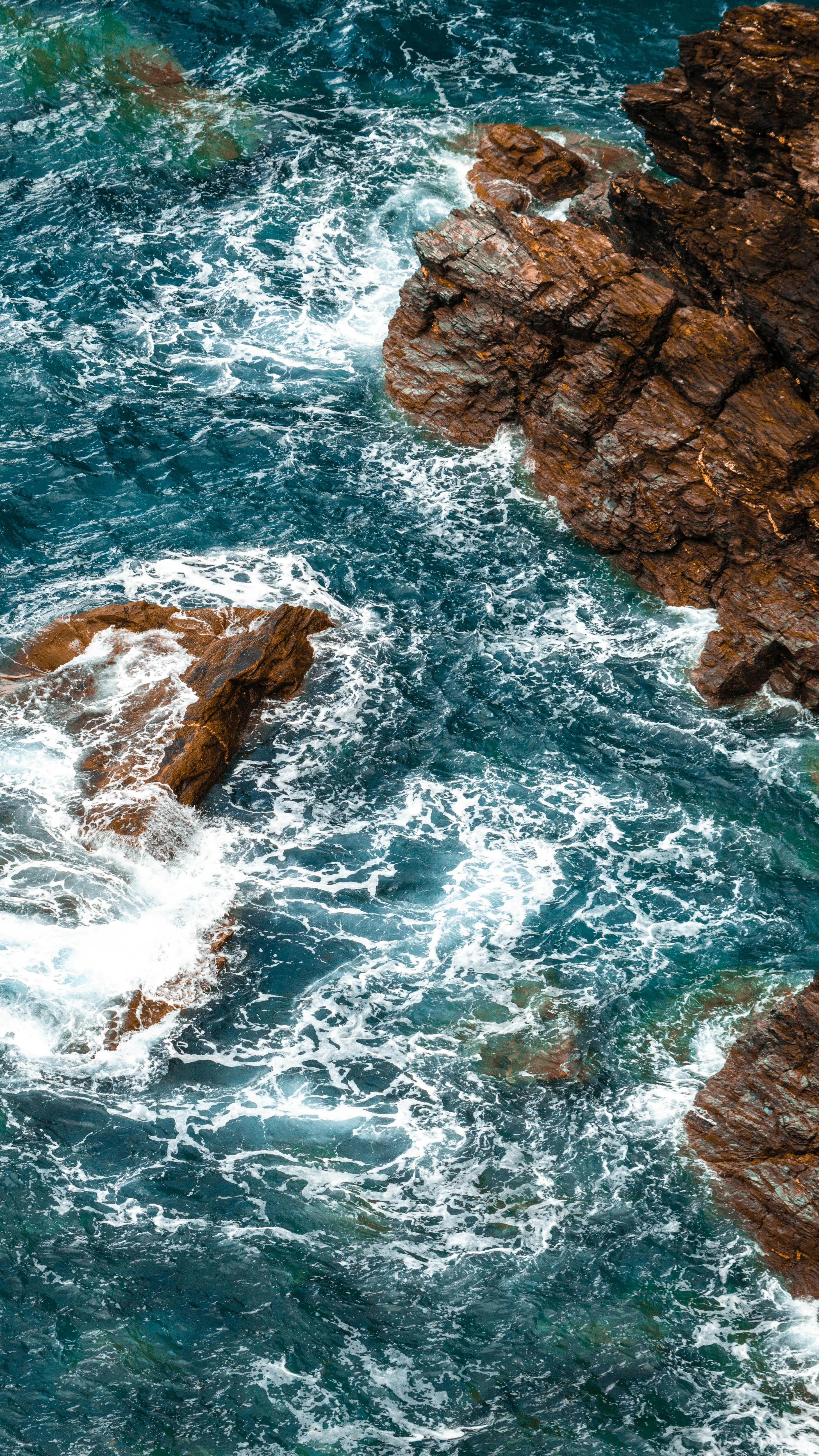 2916x5184 Ocean Waves Whirling and Crashing on Brown Rocks · Free