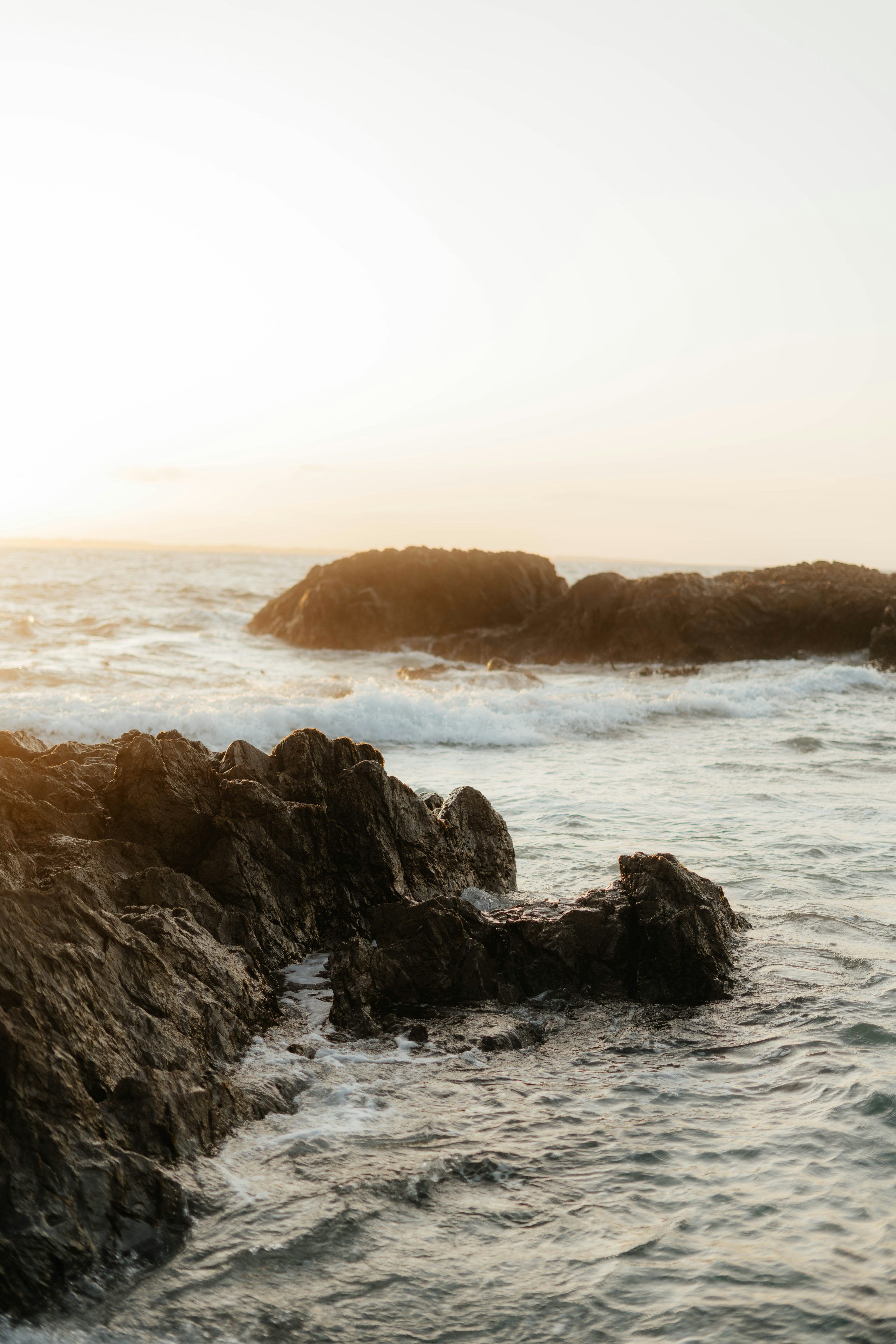 3000x4500 A person standing on a rock next to the ocean photo