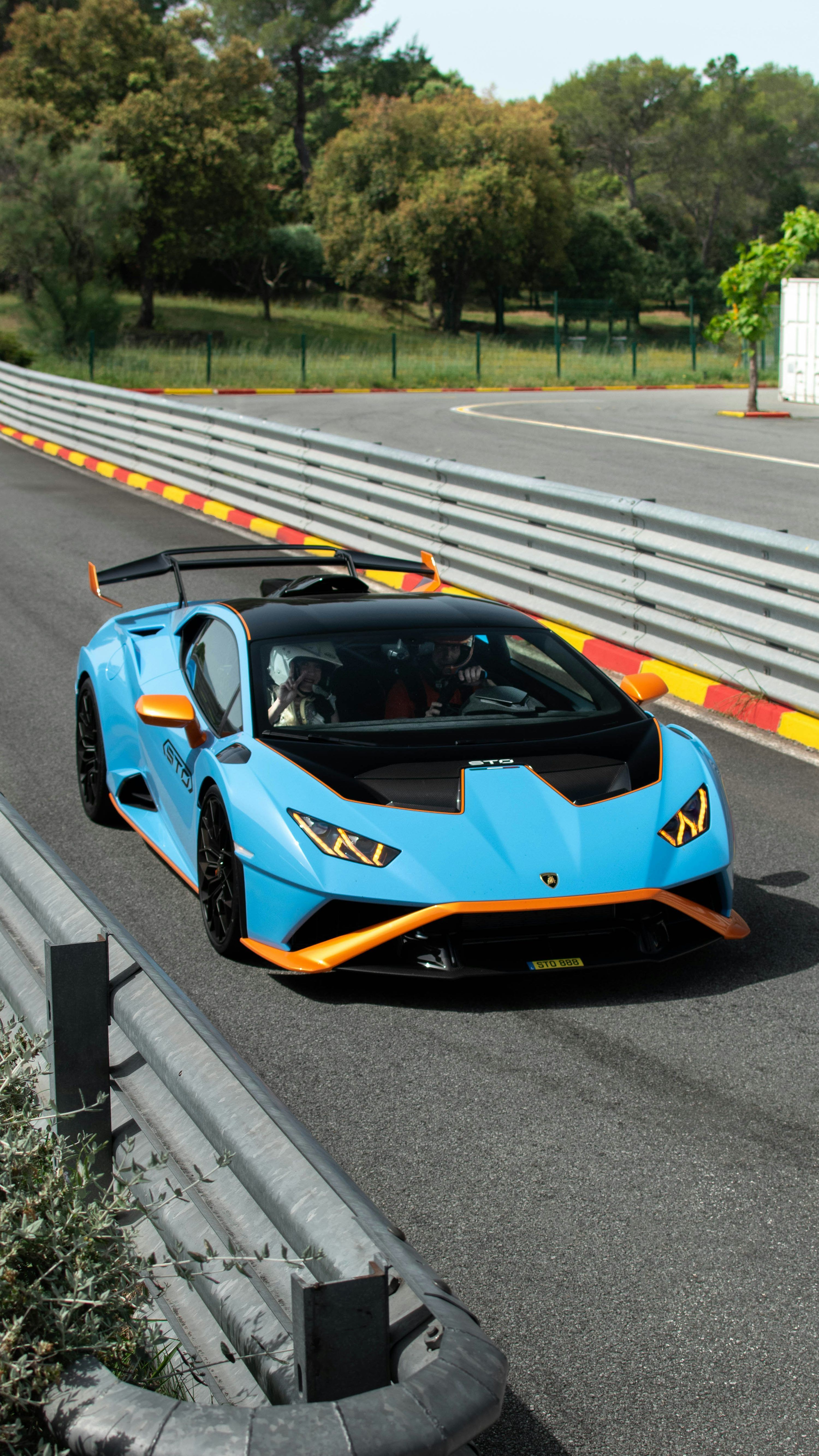 3000x5333 A blue and orange sports car driving down a race track photo