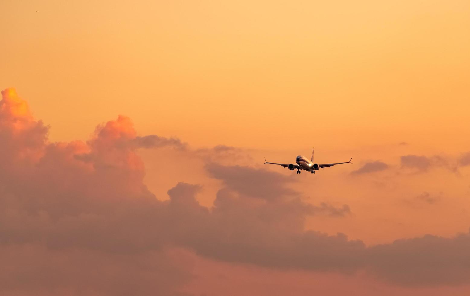 1557x980 Commercial airline. Passenger plane landing at airport with beautiful sunset sky and clouds. Arrival flight. Airplane flying in a line for landing. Aircraft open light in the evening flight. 7771596
