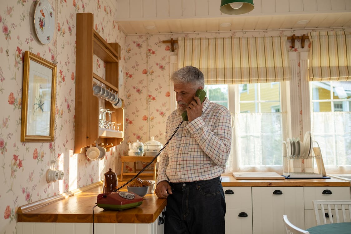 1125x750 Senior Man Talking On Landline Phone In Old Fashioned Kitchen · Free