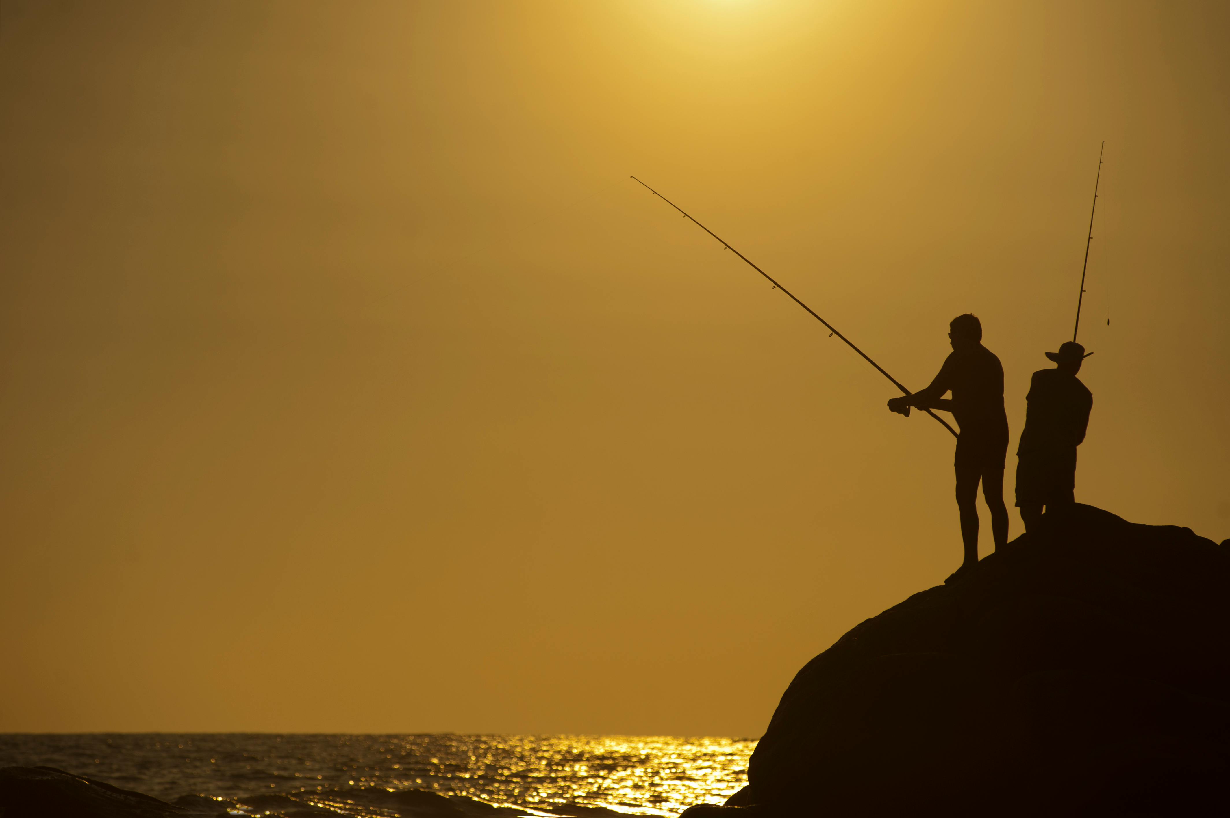 4256x2832 Silhouette Photo of Two Men Holding Fishing Rods Against Body of Water on Hill · Free