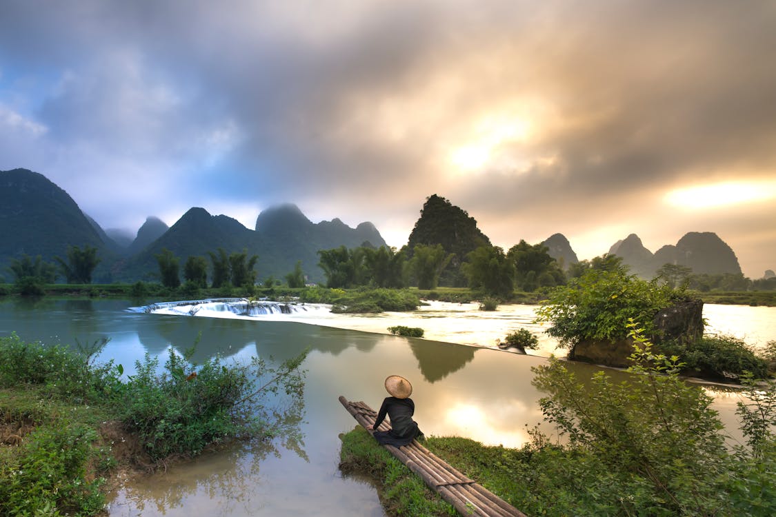 1125x750 Person Sitting on Bamboo Near Body of Water · Free