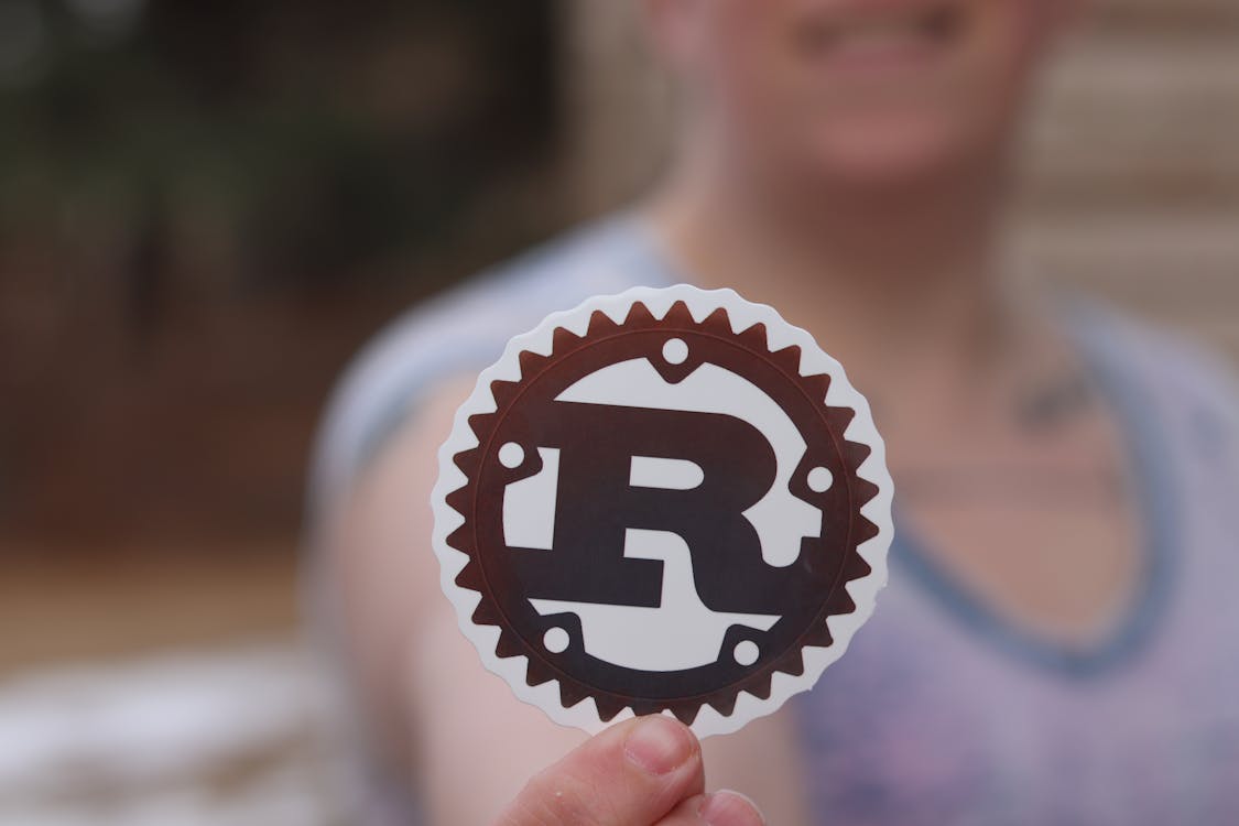 1125x750 Close Up Of Man Holding A Cutout With The Logo Of Rust Programming Language · Free