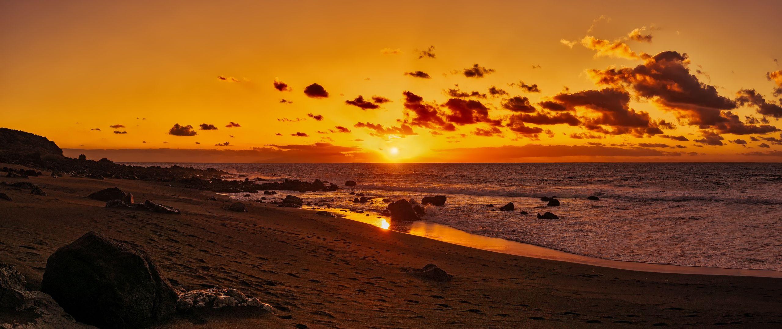 2560x1080 Download wallpaper 2560x1080 ocean, sunset, shore, sand, stones