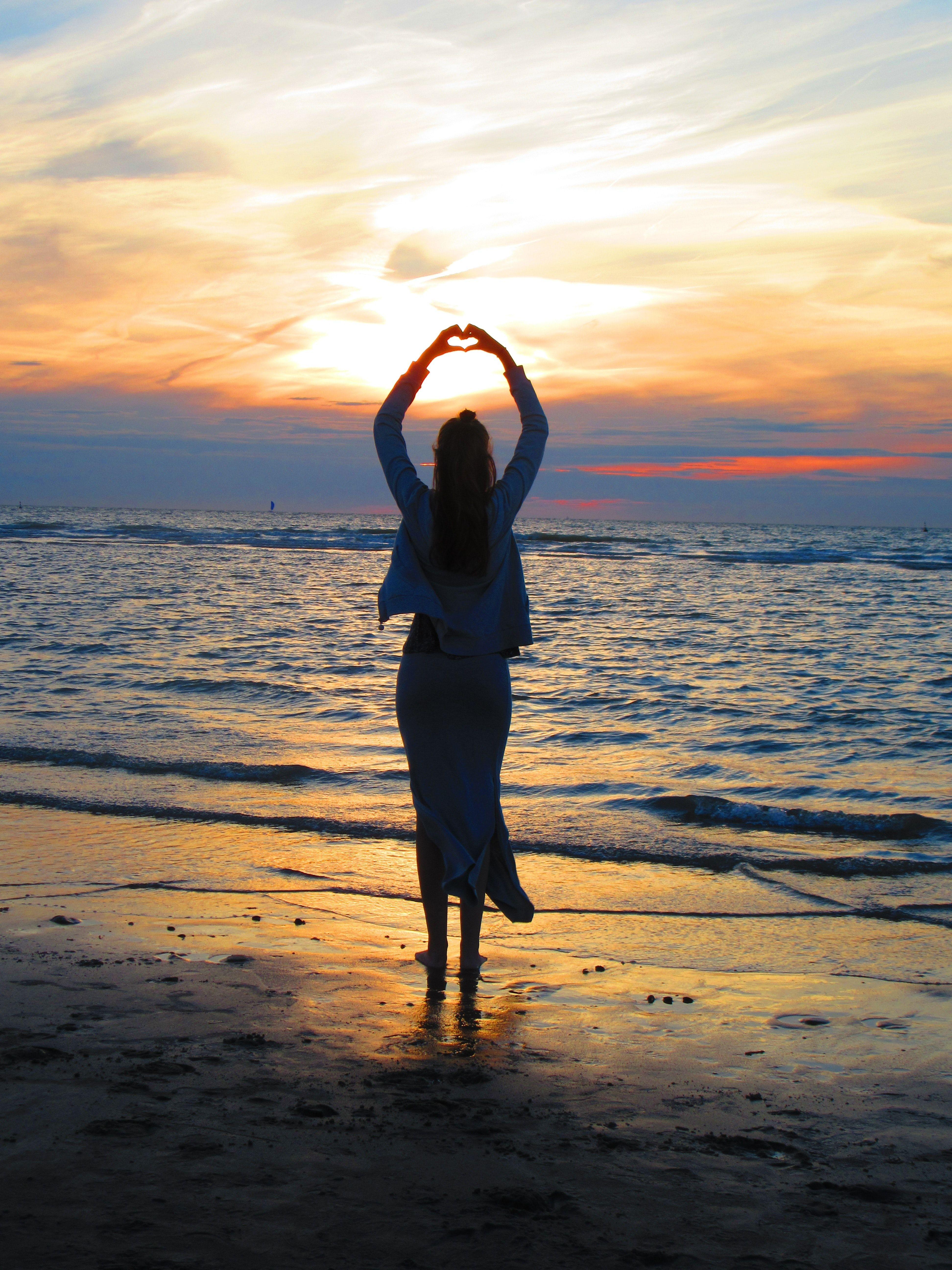 3888x5184 Woman With Arms Up Making Heart Sign While Standing on Beach at