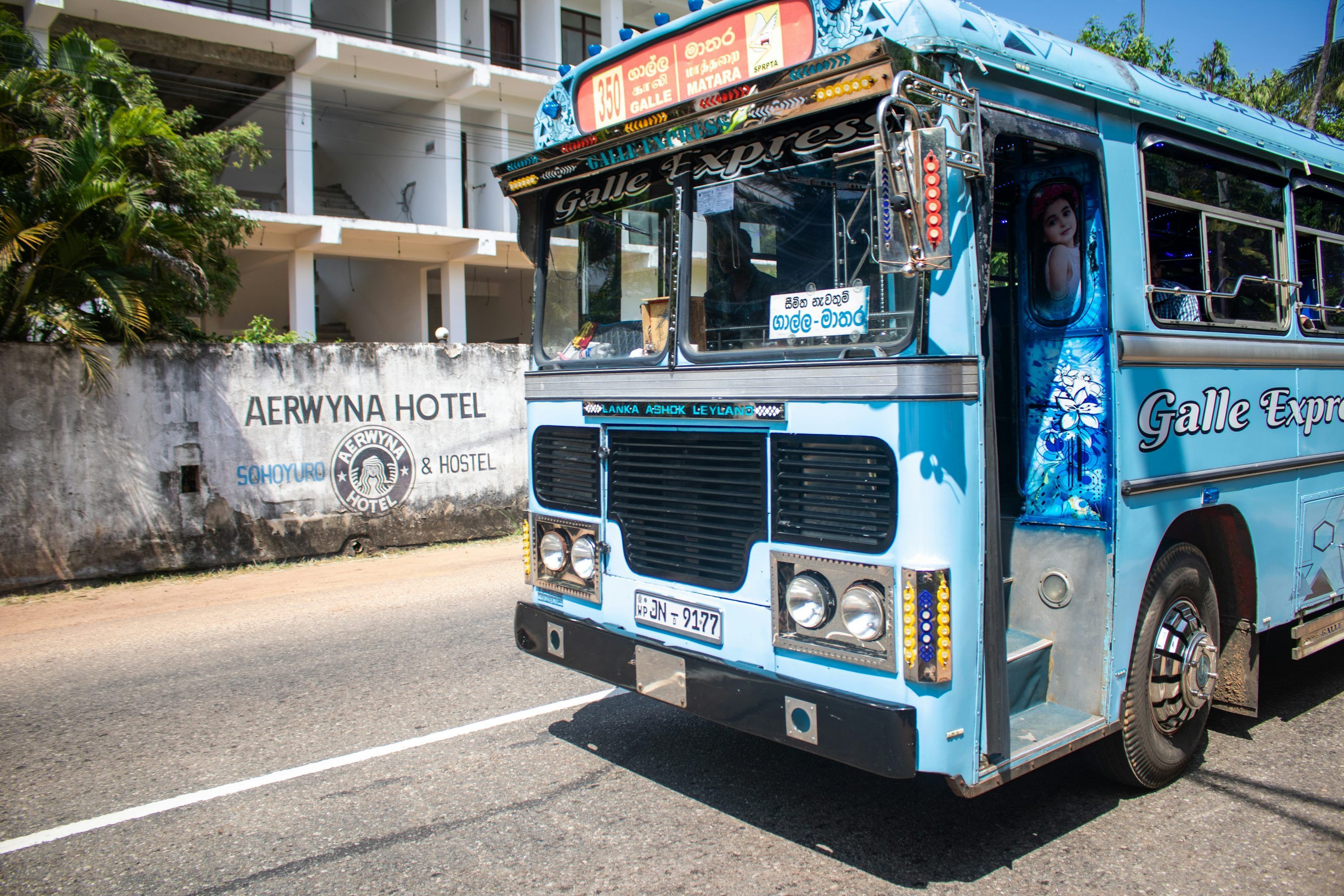 3000x2000 A blue bus drives down a sunny street. photo