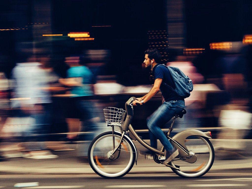1024x768 Man Riding Bicycle on City Street HD Wallpaper
