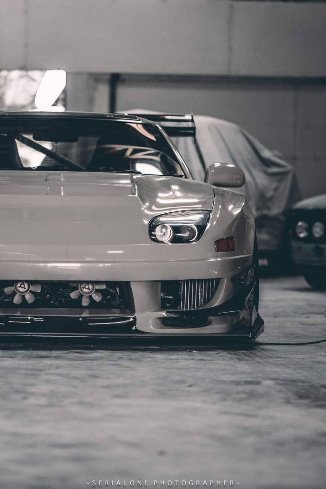 1045x1567 Download a white sports car parked in a garage Wallpaper