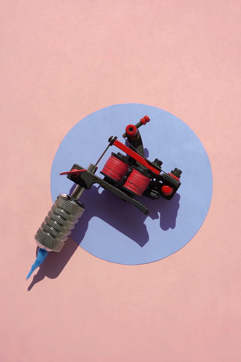 800x1199 Black and red tattoo machine on pink surface, HD phone wallpaper
