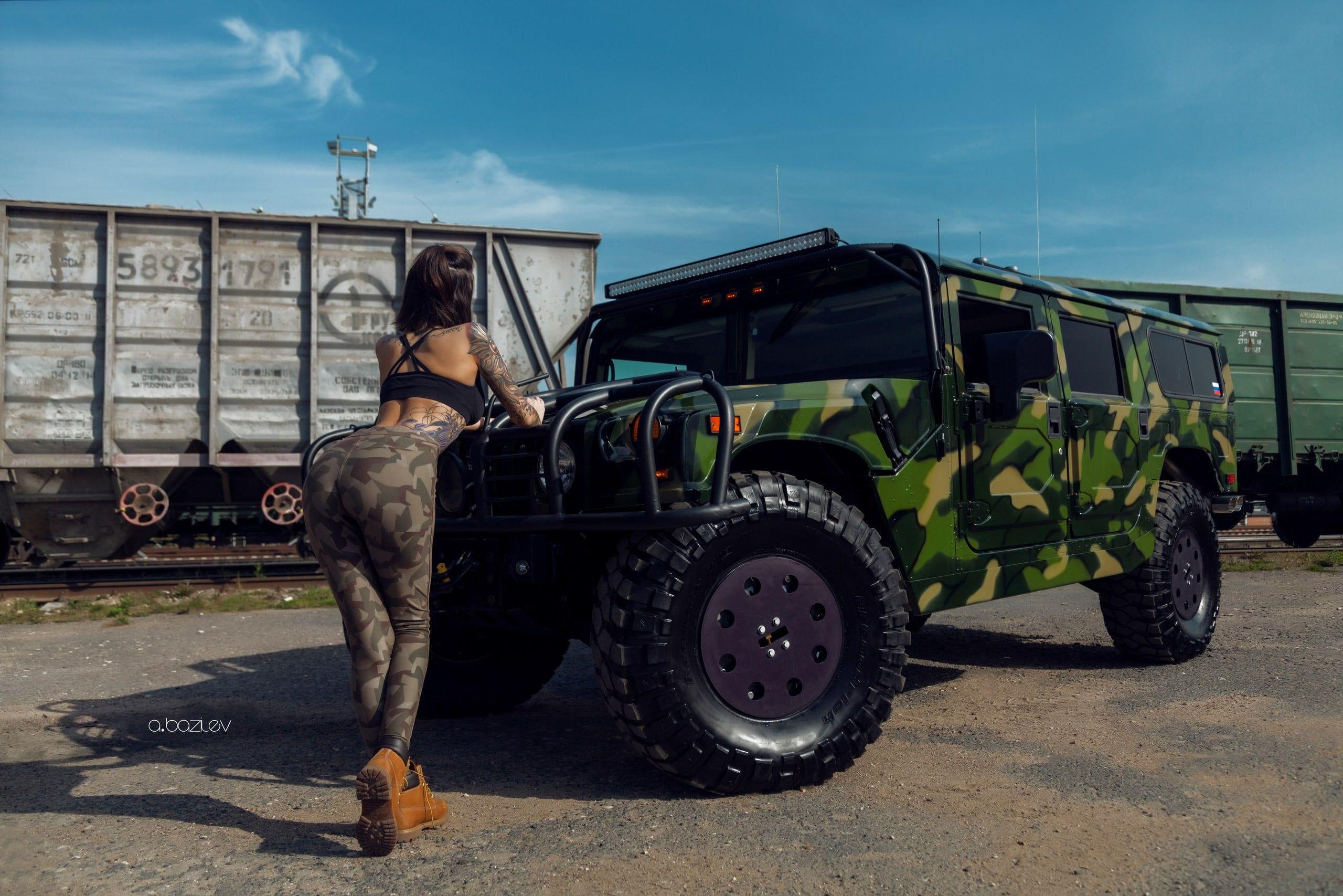 2560x1707 Woman in brown camouflage pants standing infront of green