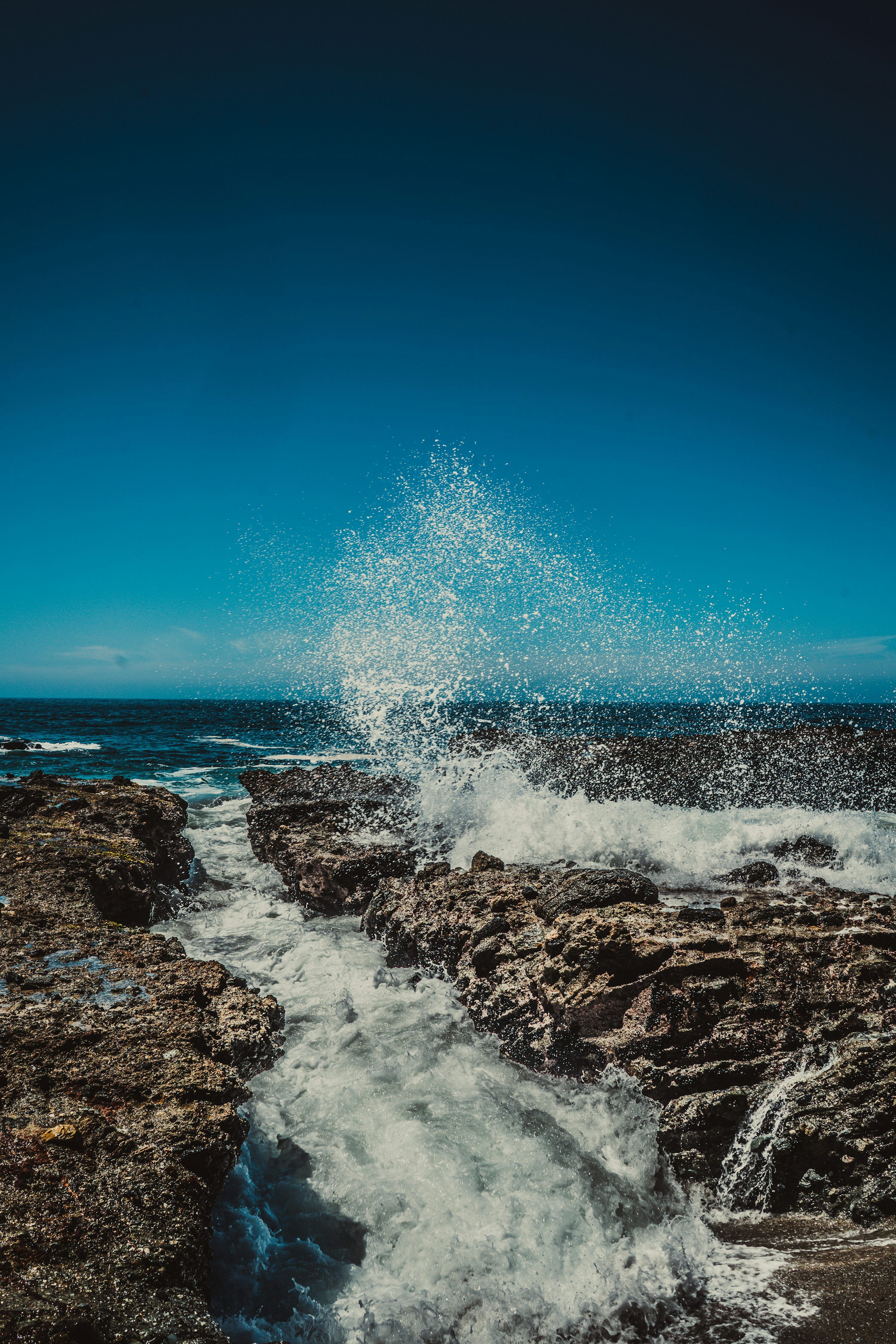 3000x4497 Water splashing on rock under blue sky photo