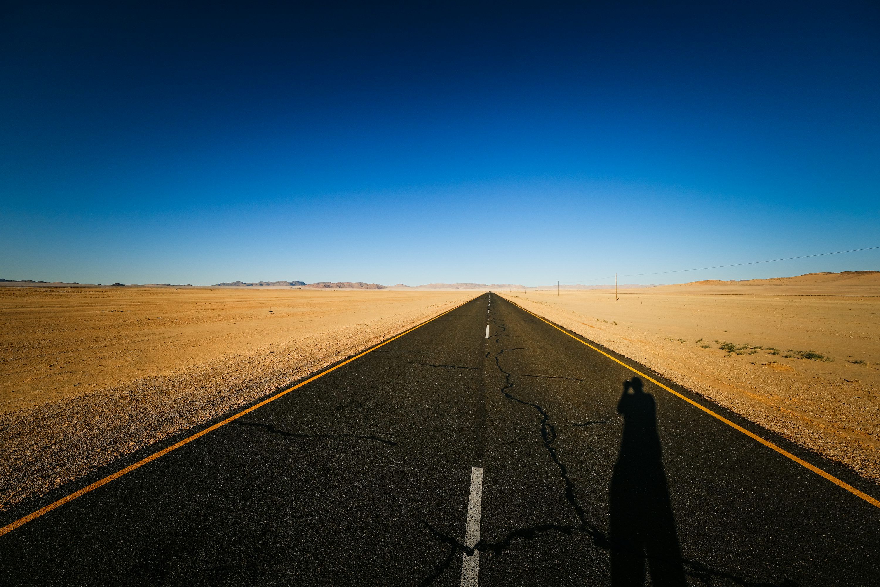 3000x2000 A person standing on a road in the middle of nowhere photo