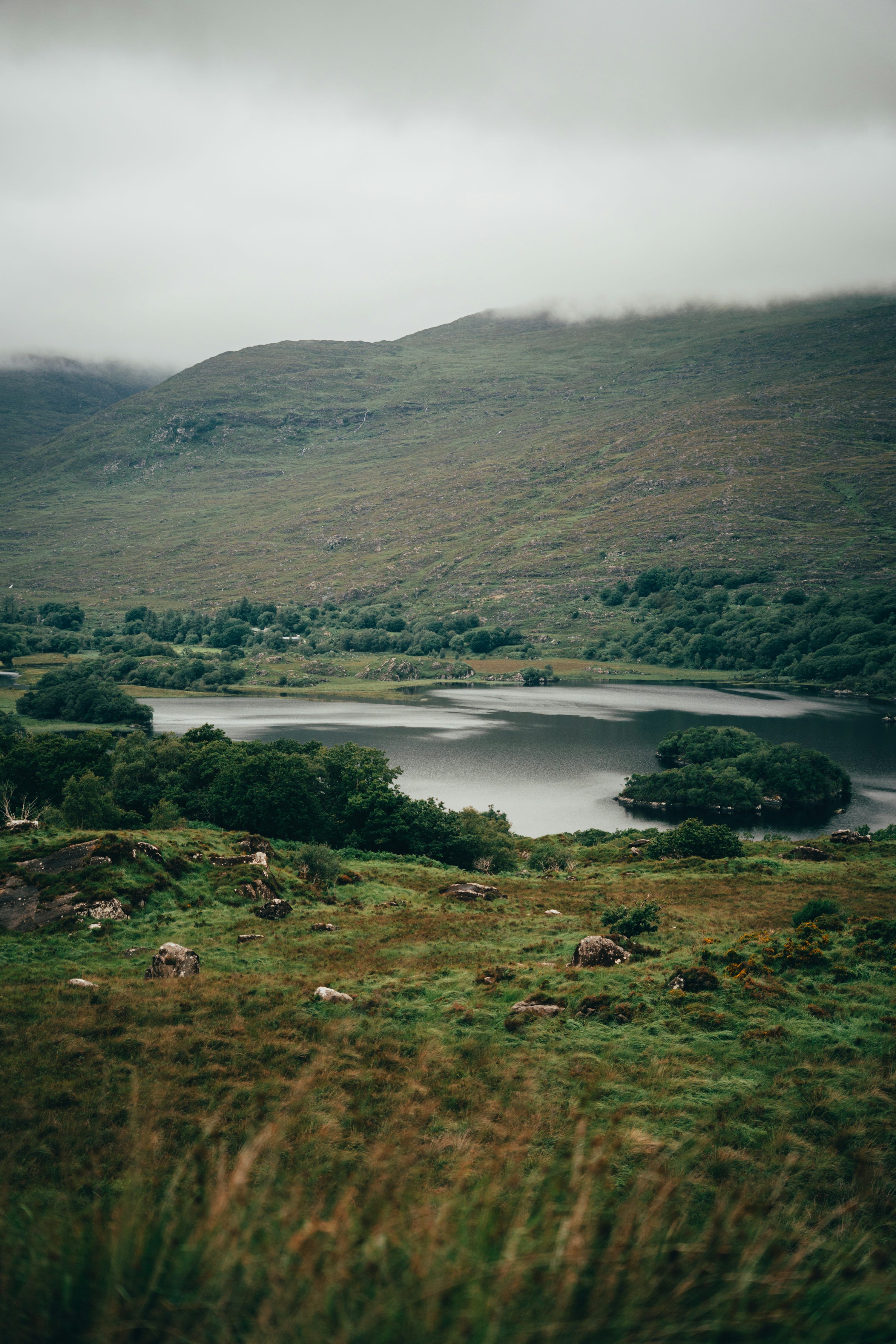 3000x4500 Misty mountains overlook a serene lake and green landscape. photo