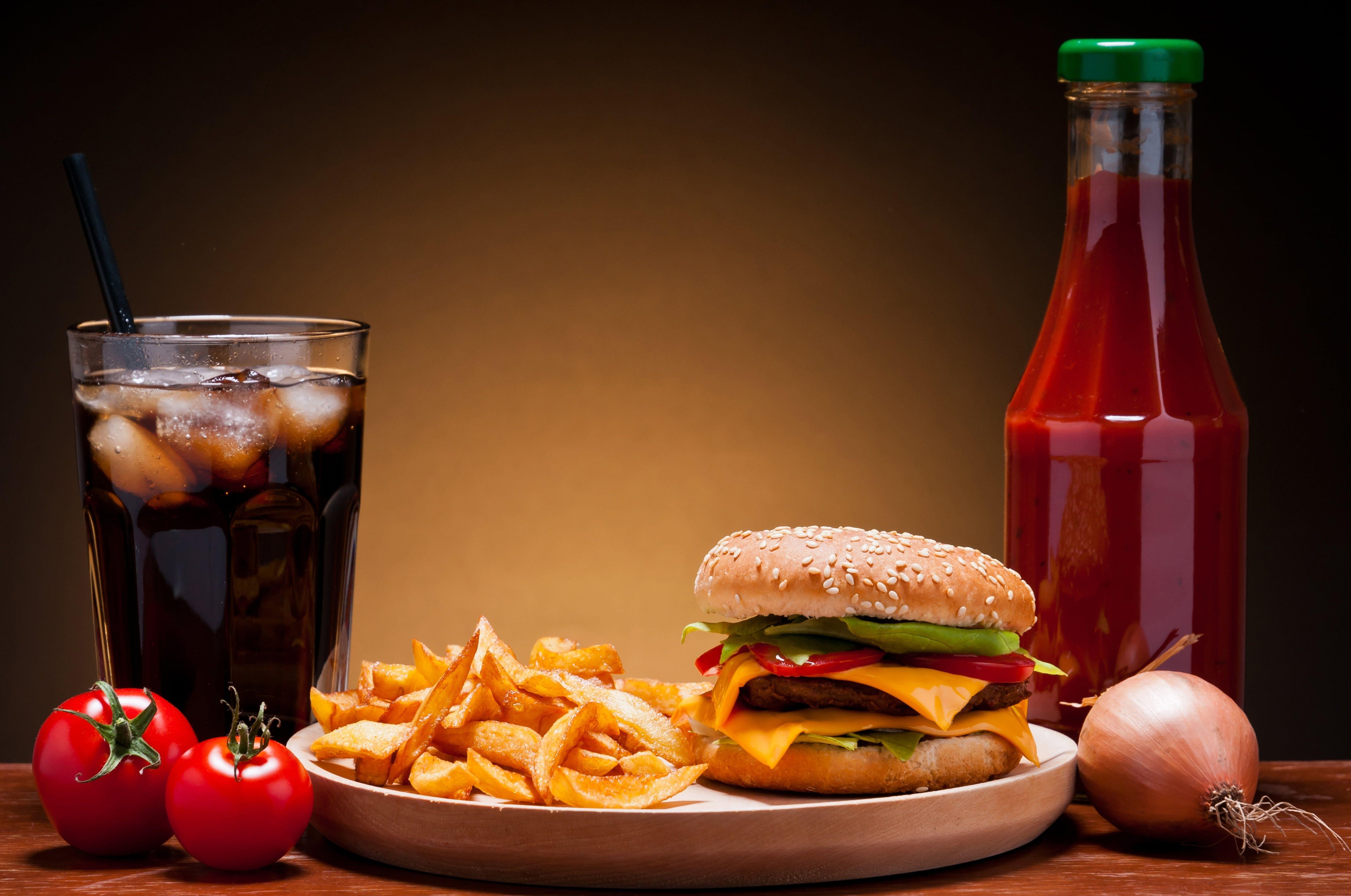 5800x3849 Burger with fries on plate beside soda on drinking glass
