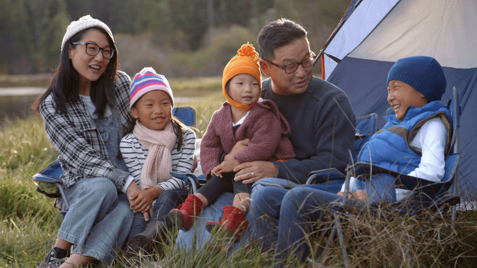 1920x1080 Asian family on a camping trip talking outside their tent Stock