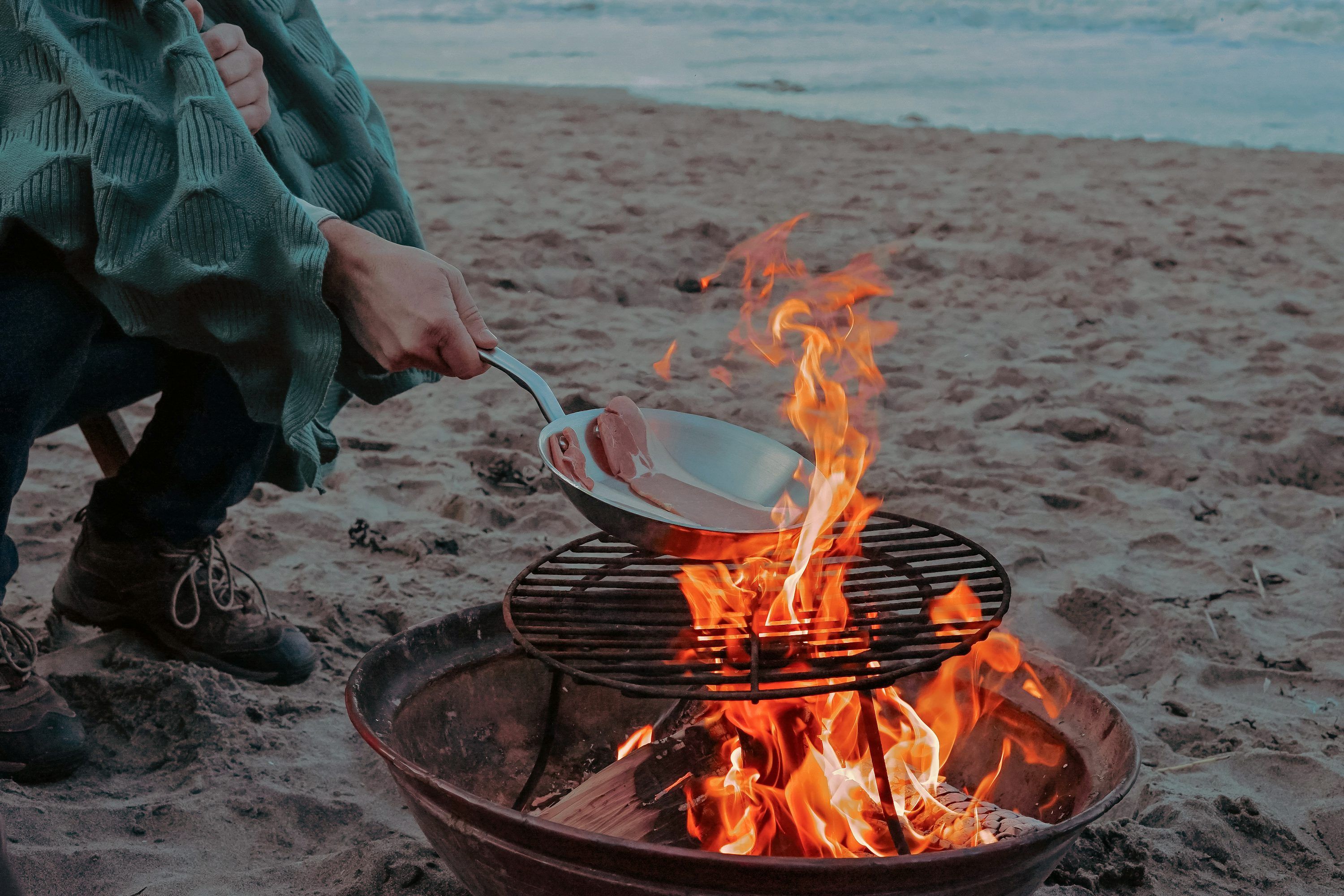 3000x2000 Person cooking meat on bonfire near shoreline photo