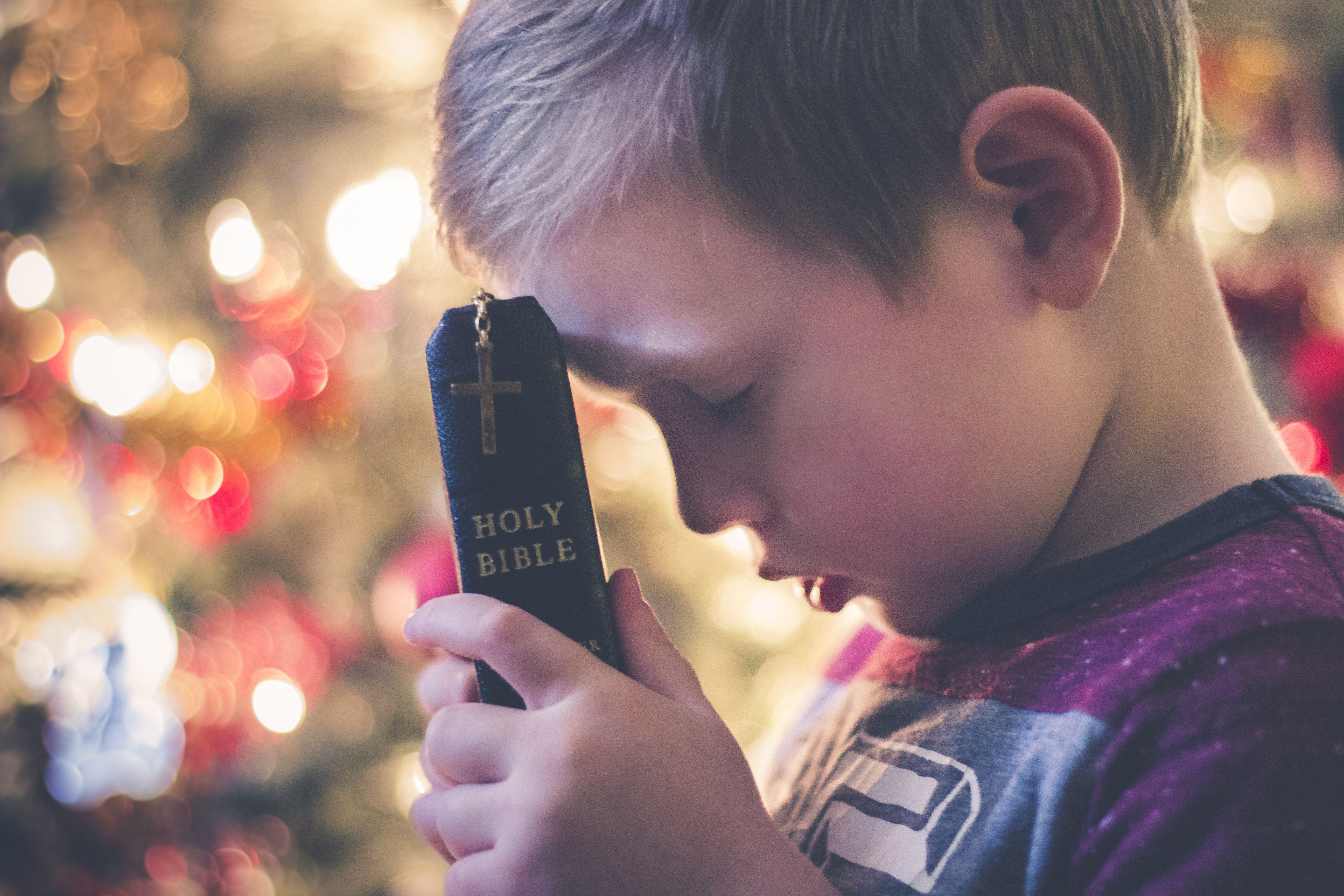5184x3456 focused photo of a boy holding the bible praying wearing purple