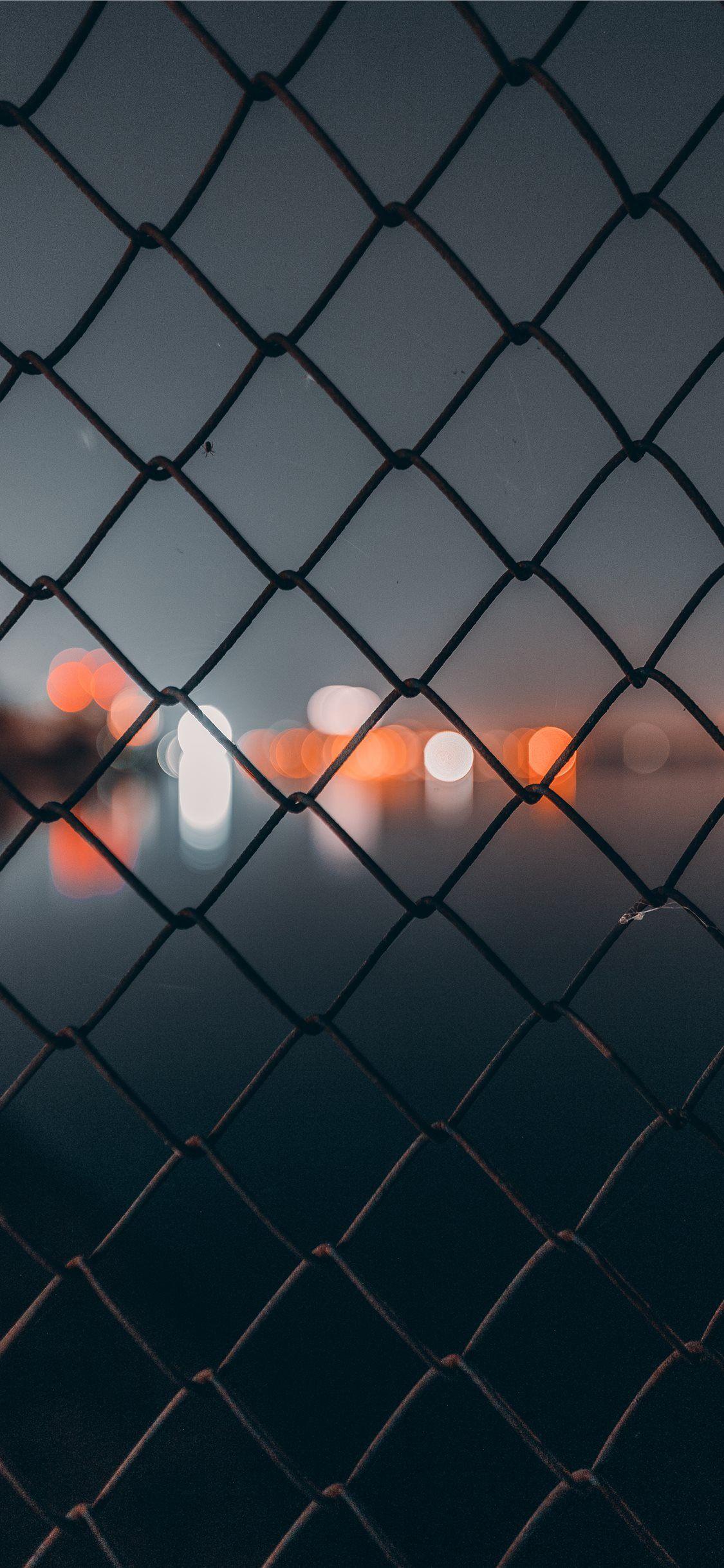 1125x2436 chain link fence behind bokeh iPhone X Wallpaper Free Download