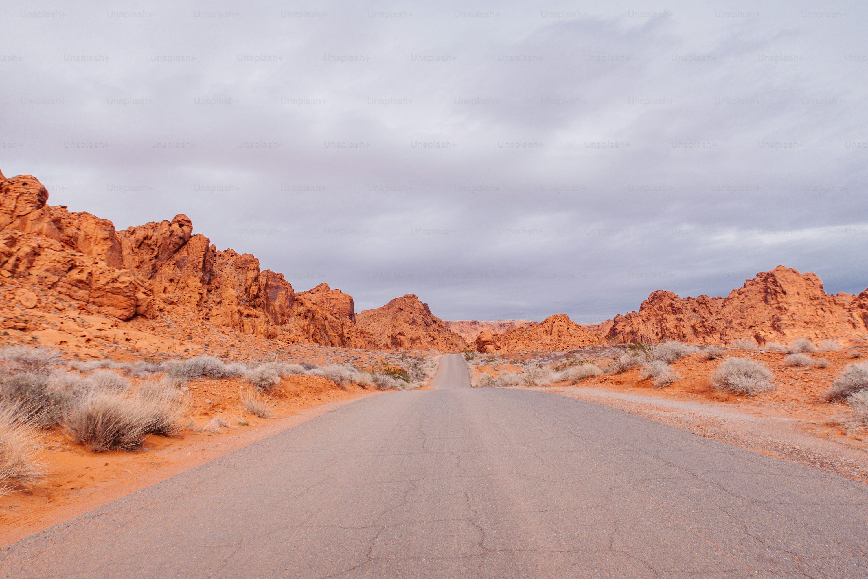 3000x2000 A road in the middle of a desert with mountains in the background photo