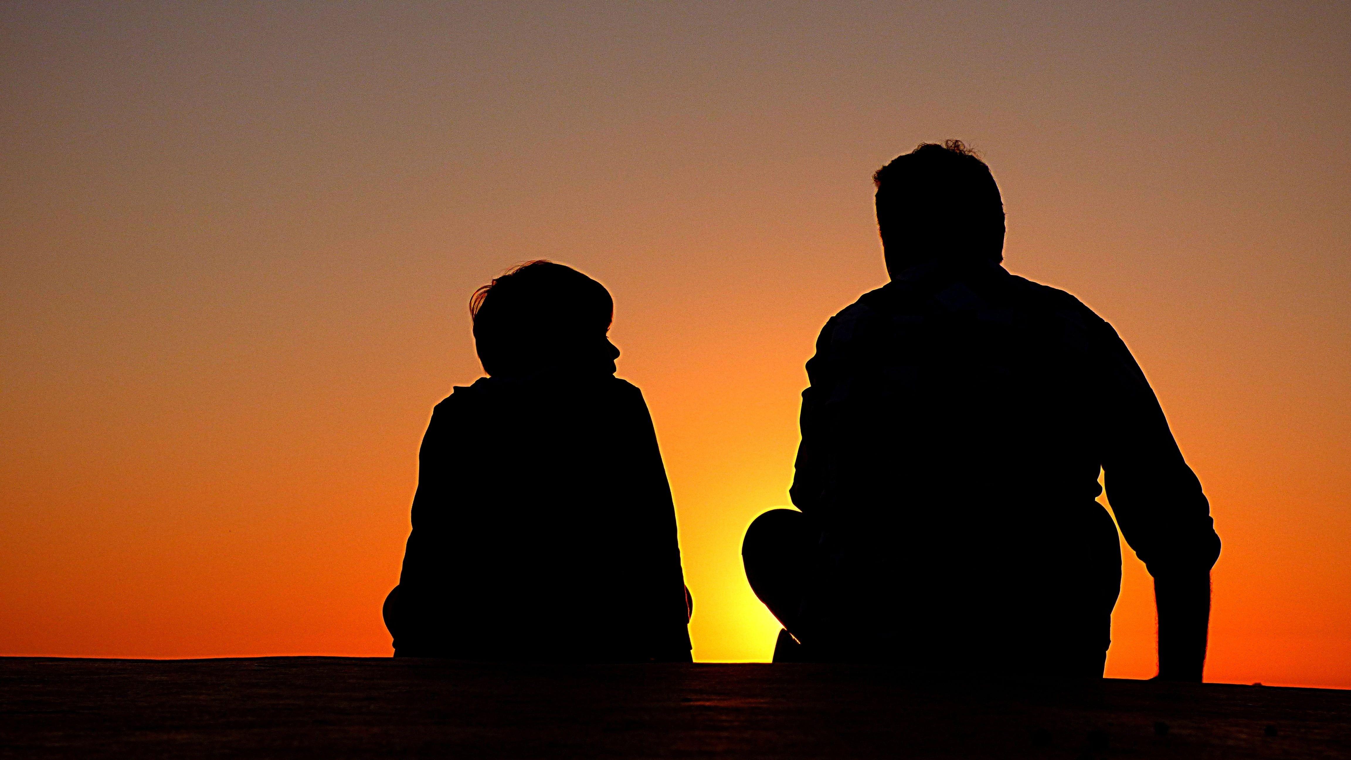4608x2592 Silhouette of man and boy sitting on ground with yellow background
