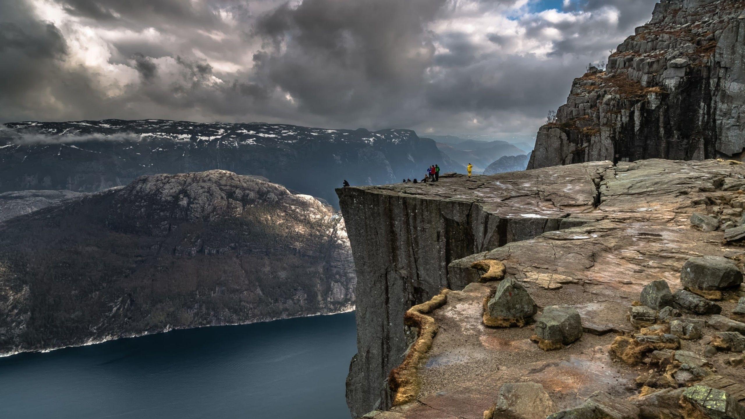 2560x1440 Download 2560x1440 Cliff, Mountains, Dark Clouds, People