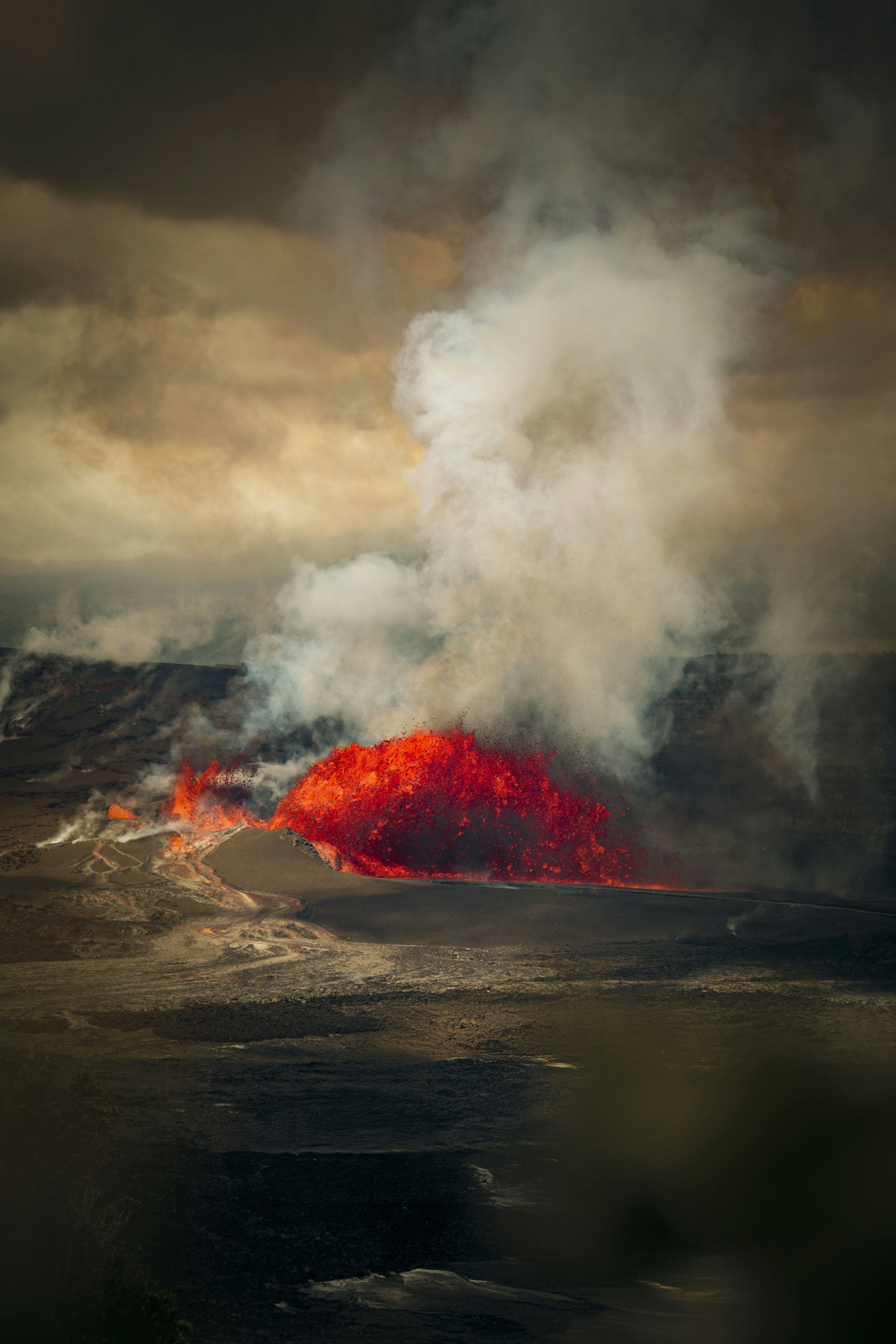 3000x4500 Molten lava erupting from a volcano under cloudy skies. photo