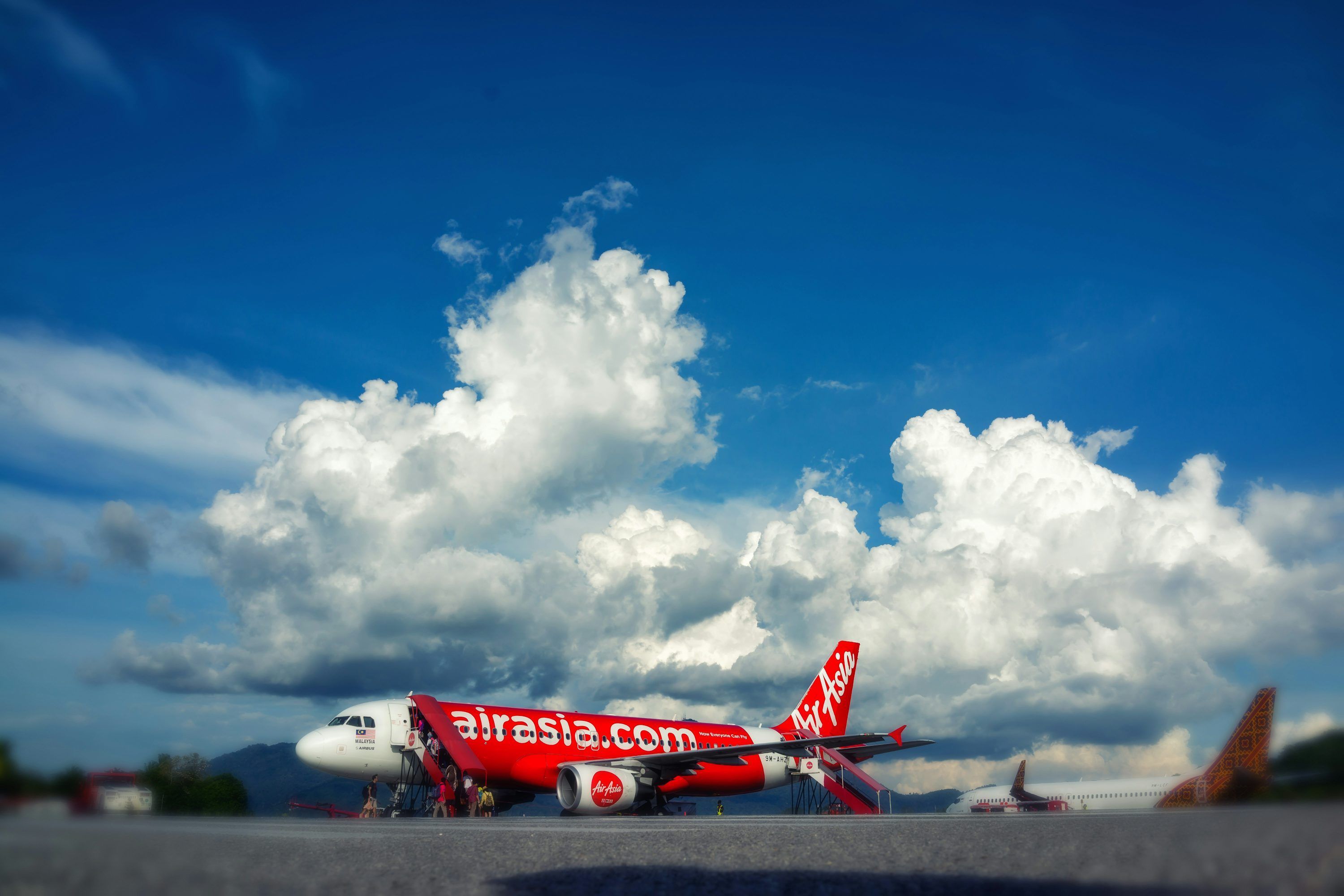 3000x2000 An airasia airplane parked on tarmac with hangar behind. photo