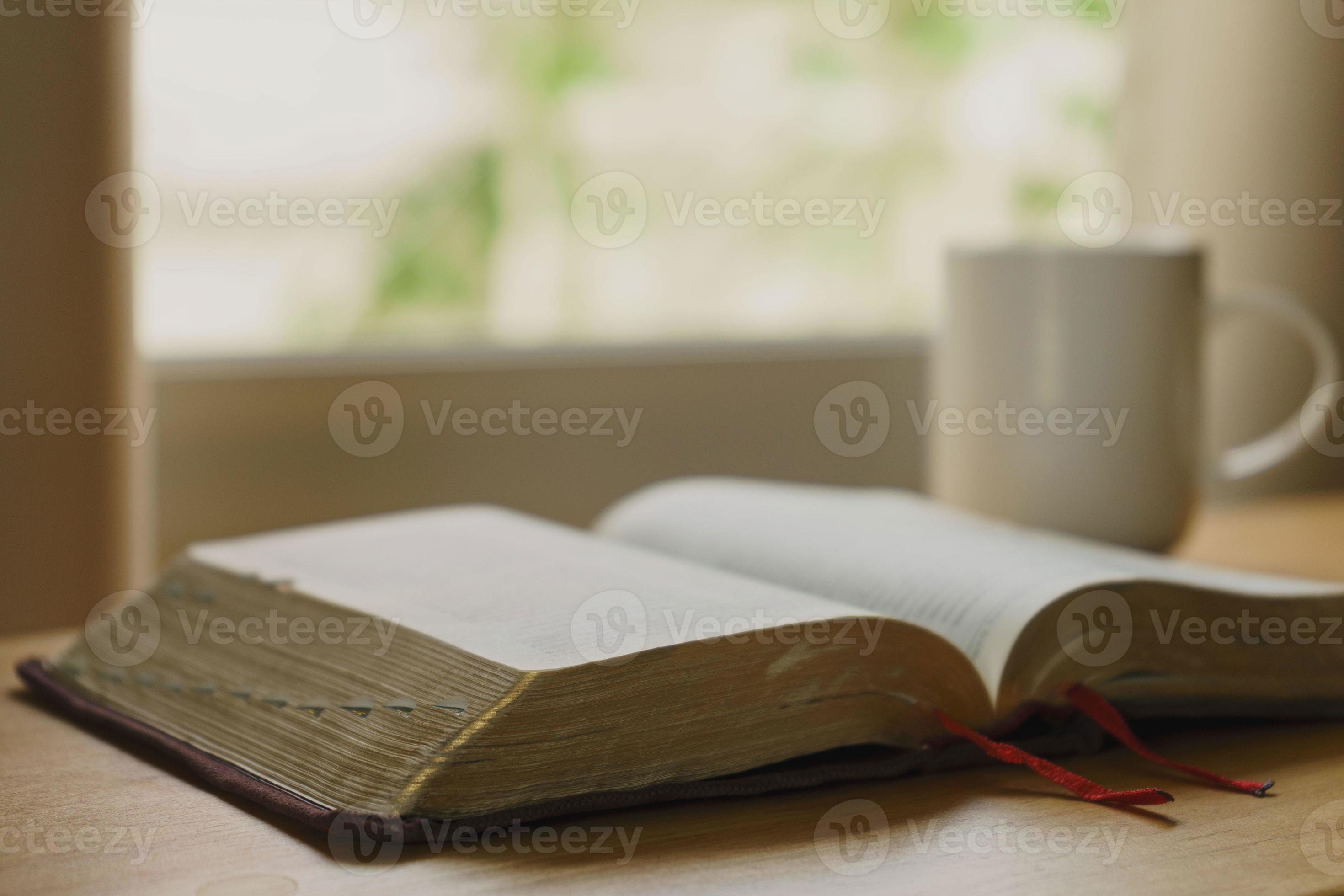 2940x1960 Close up of open bible with a cup of coffee for morning devotion on wooden table with window light. Christian background
